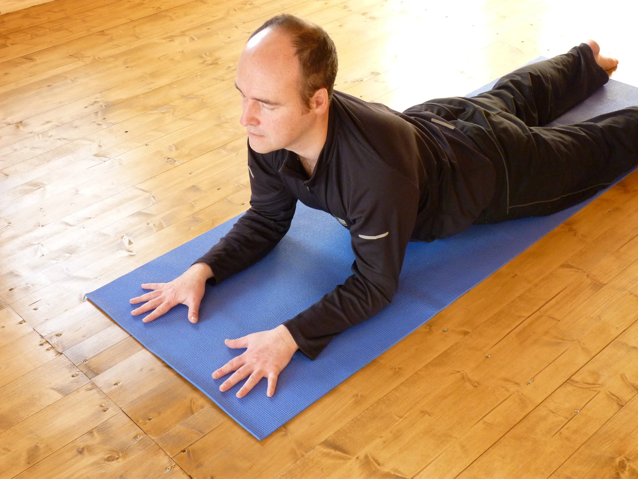 Person performing yoga pose on blue mat indoors
