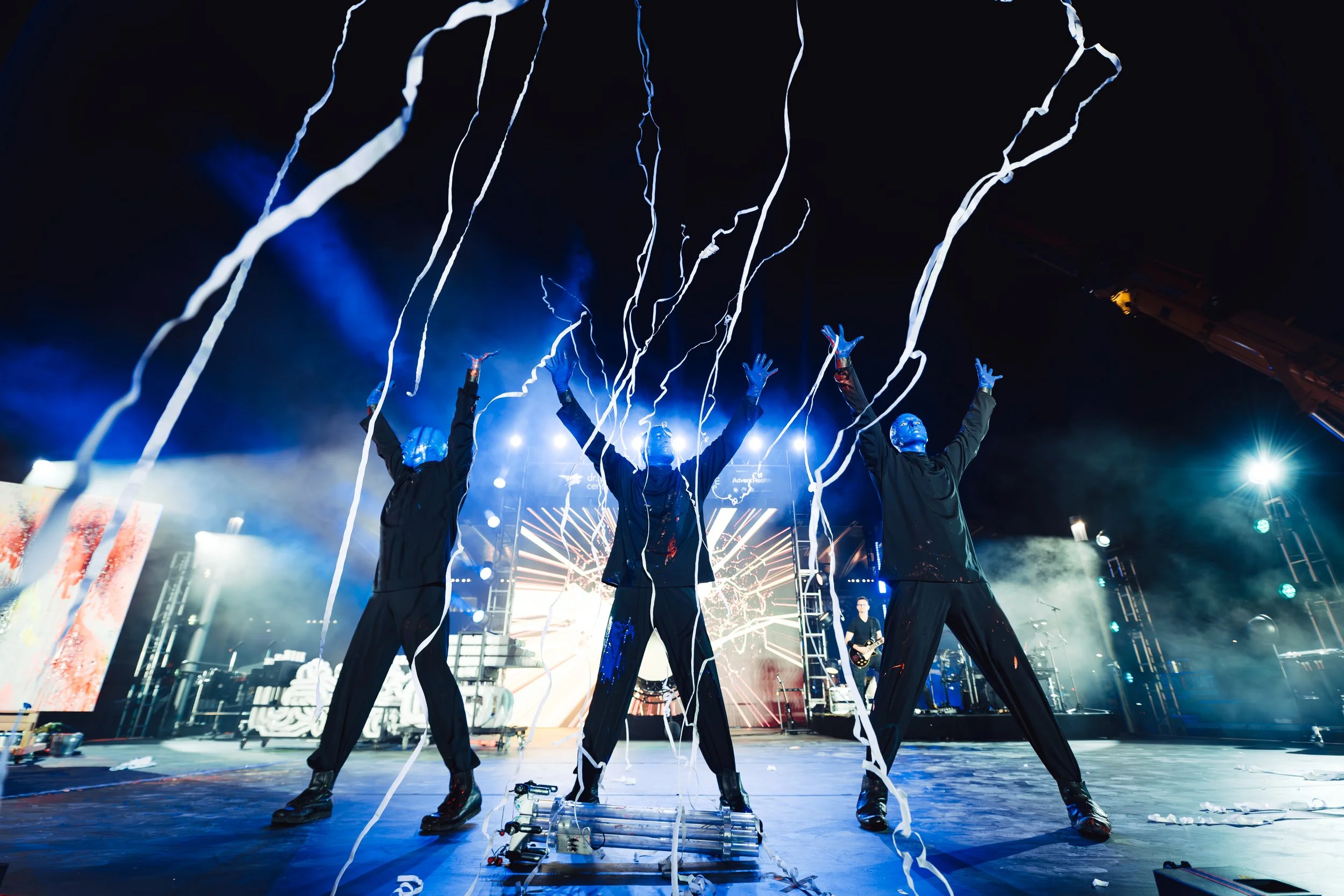 Blue Man Group performs on stage with streamers in the air on stage at IMMERSE in Downtown Orlando