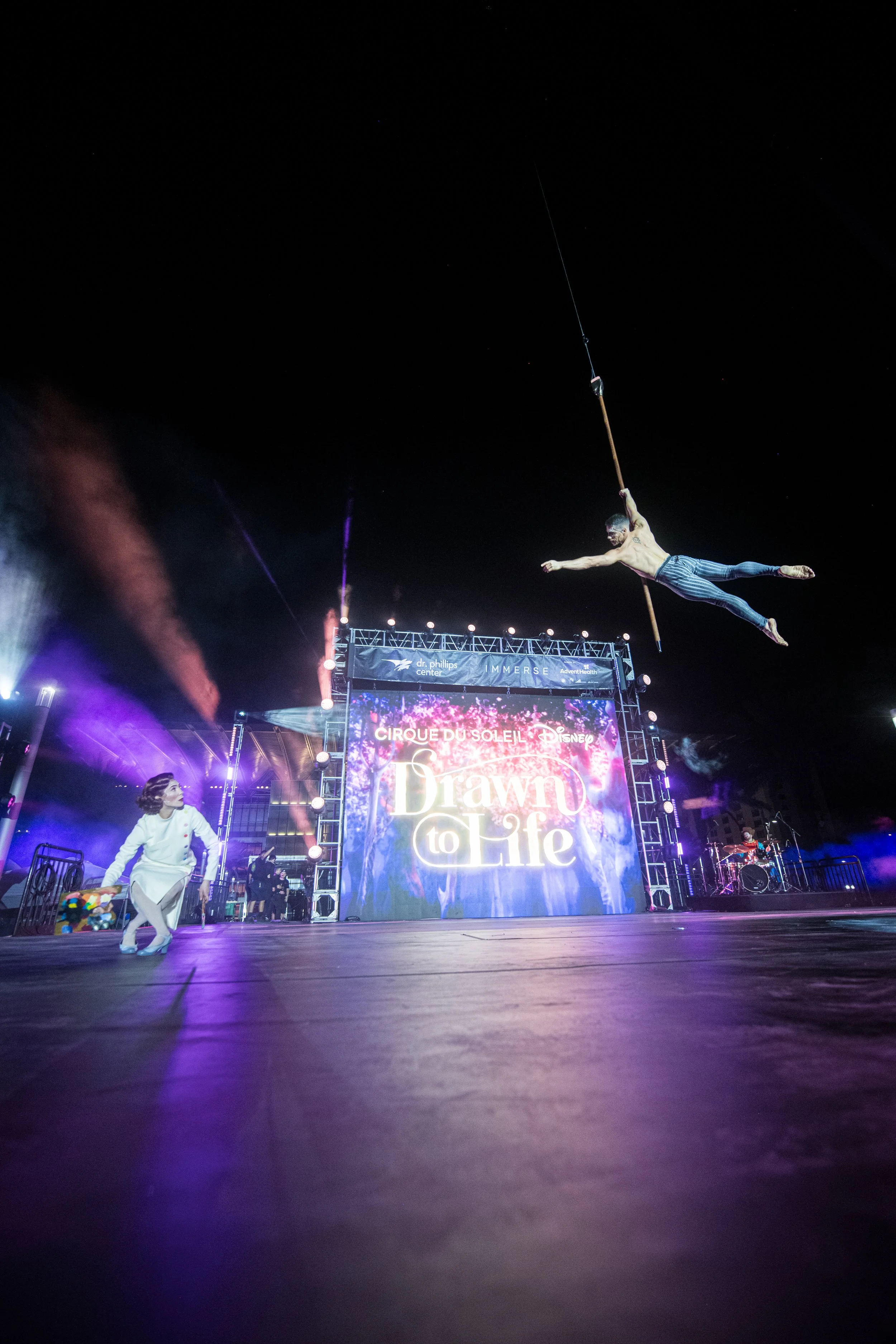 Acrobats and performers from Cirque du Soleil perform on a stage in Downtown Orlando