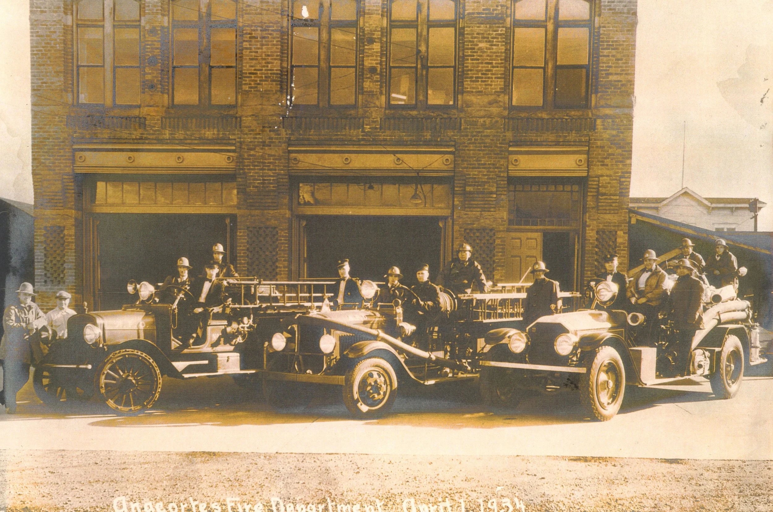  Three trucks and 14 men of the Anacortes Fire Department in front of the Fire Station/City Hall, 5th and O, 1934. (Left to right): Milton Crookston, Lou Willoughby, Bill Dorsey, Ashley Mondhan, Ed Keepers, Bill Beale, Chief Leslie E. Snider, Assista