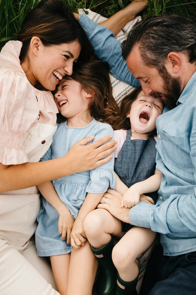 family with two girls laughing and laying on the grass-1.jpg