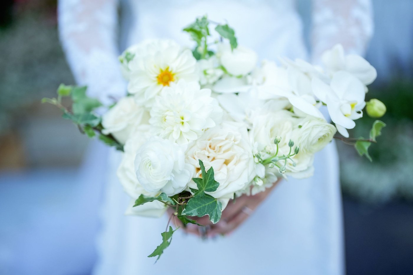 A bridal bouquet filled with white roses, ranunculus, and dahlias by Botanique of Cape Cod