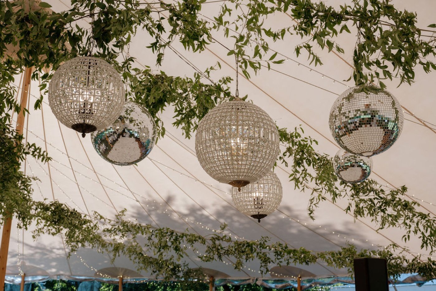 Mirror balls and crystal orbs hanging from the ceiling of a wedding tent