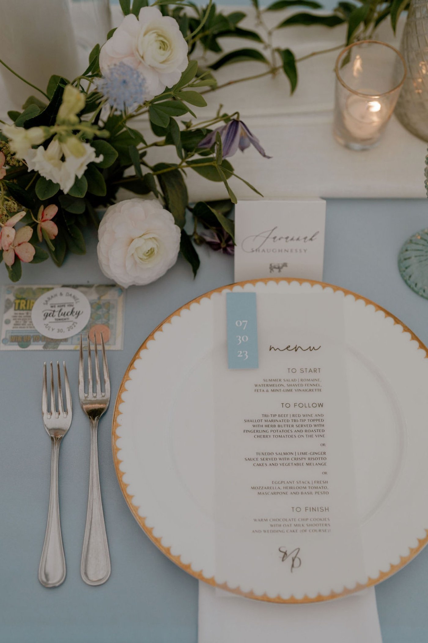 Wedding place setting with a gold rim scalloped charger plate and a vellum menu card