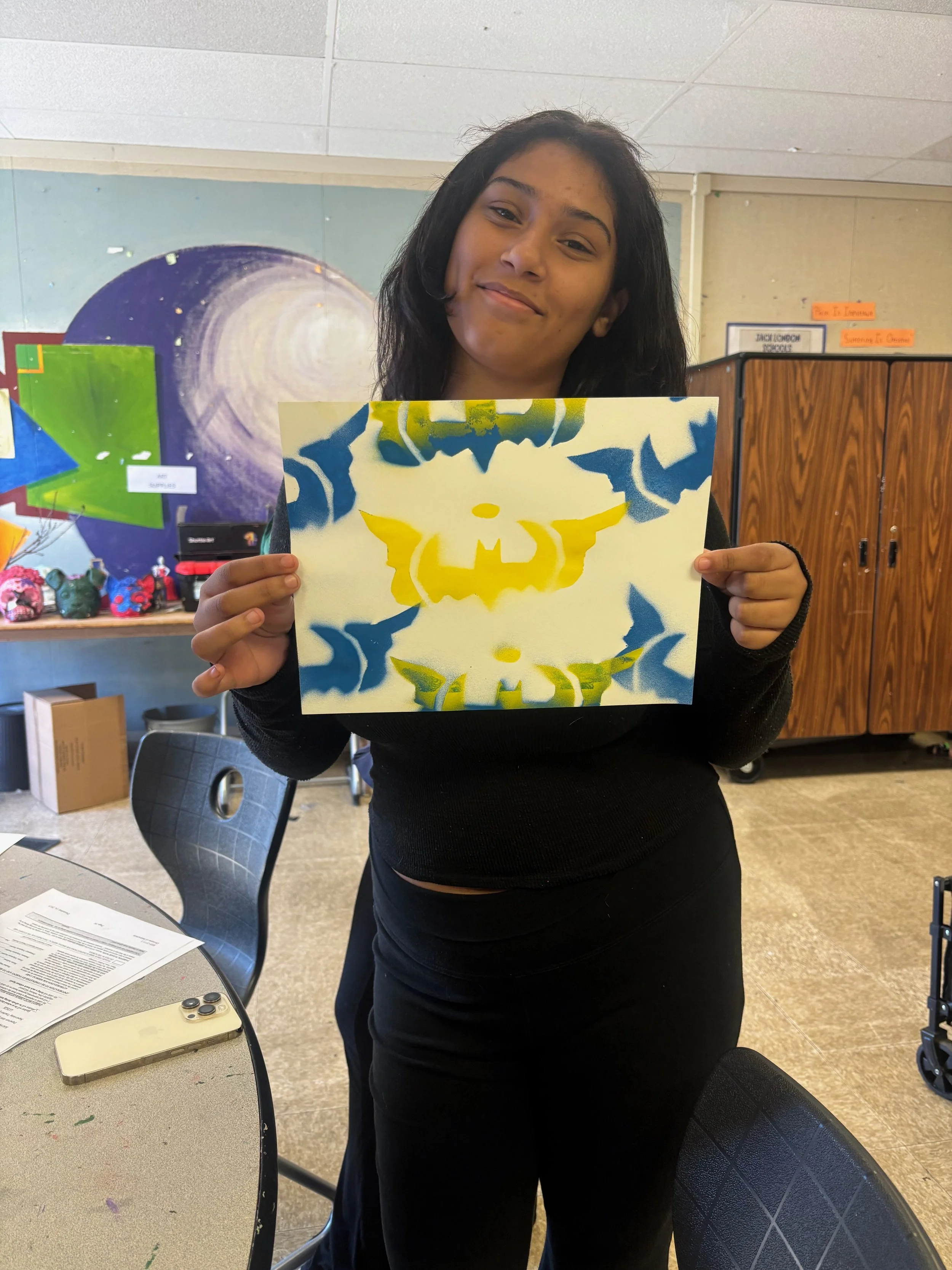 A Jack London student holds up her practice project, featuring a spray-painted stencil that she created herself. 