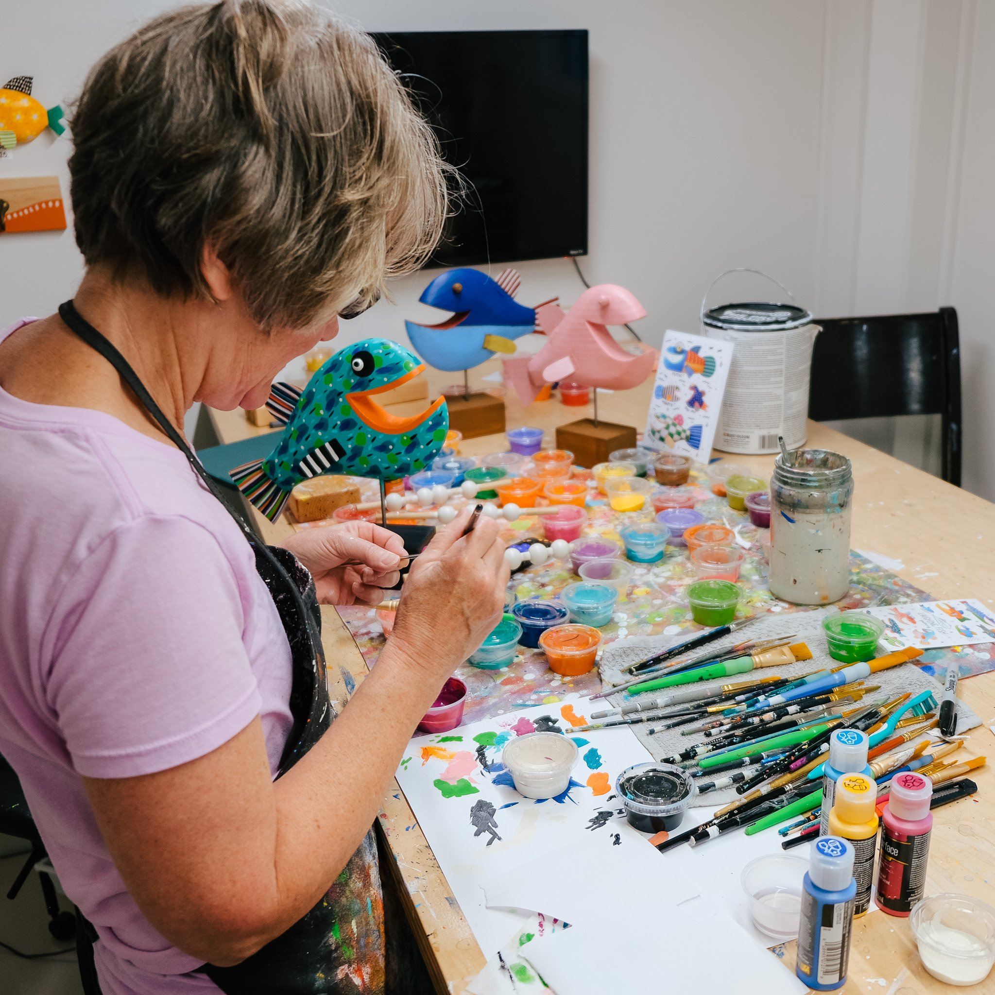 Shelly Drews, the fish artist of Michigan painting her whimsical wood creations in her studio