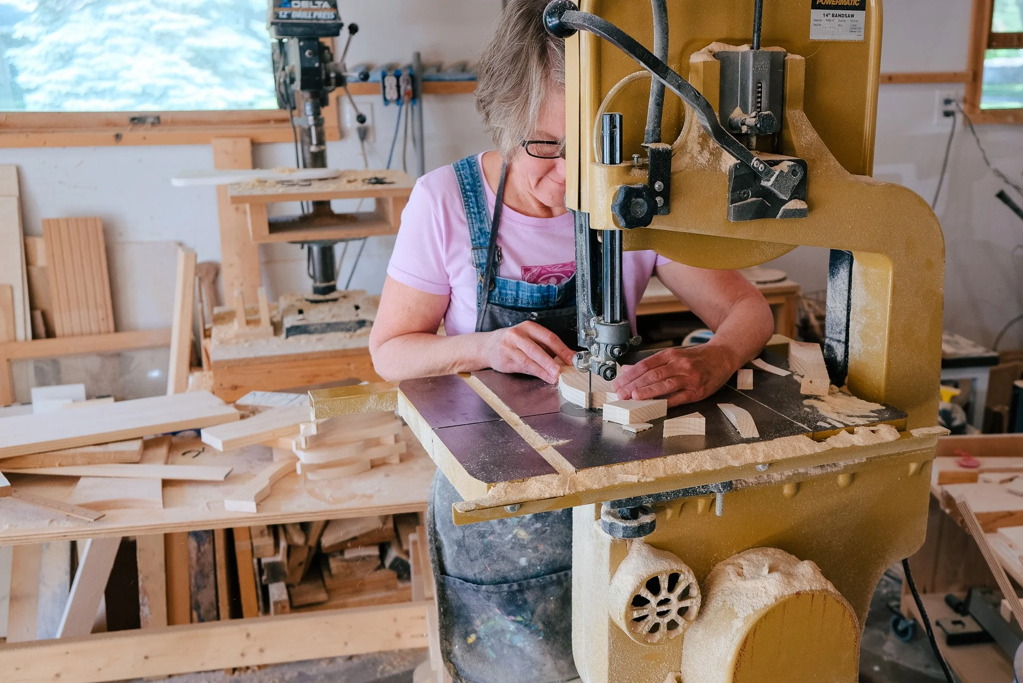 Shelly Drews carving with her band saw to carve out happy wooden fish and other whimsical wood creations