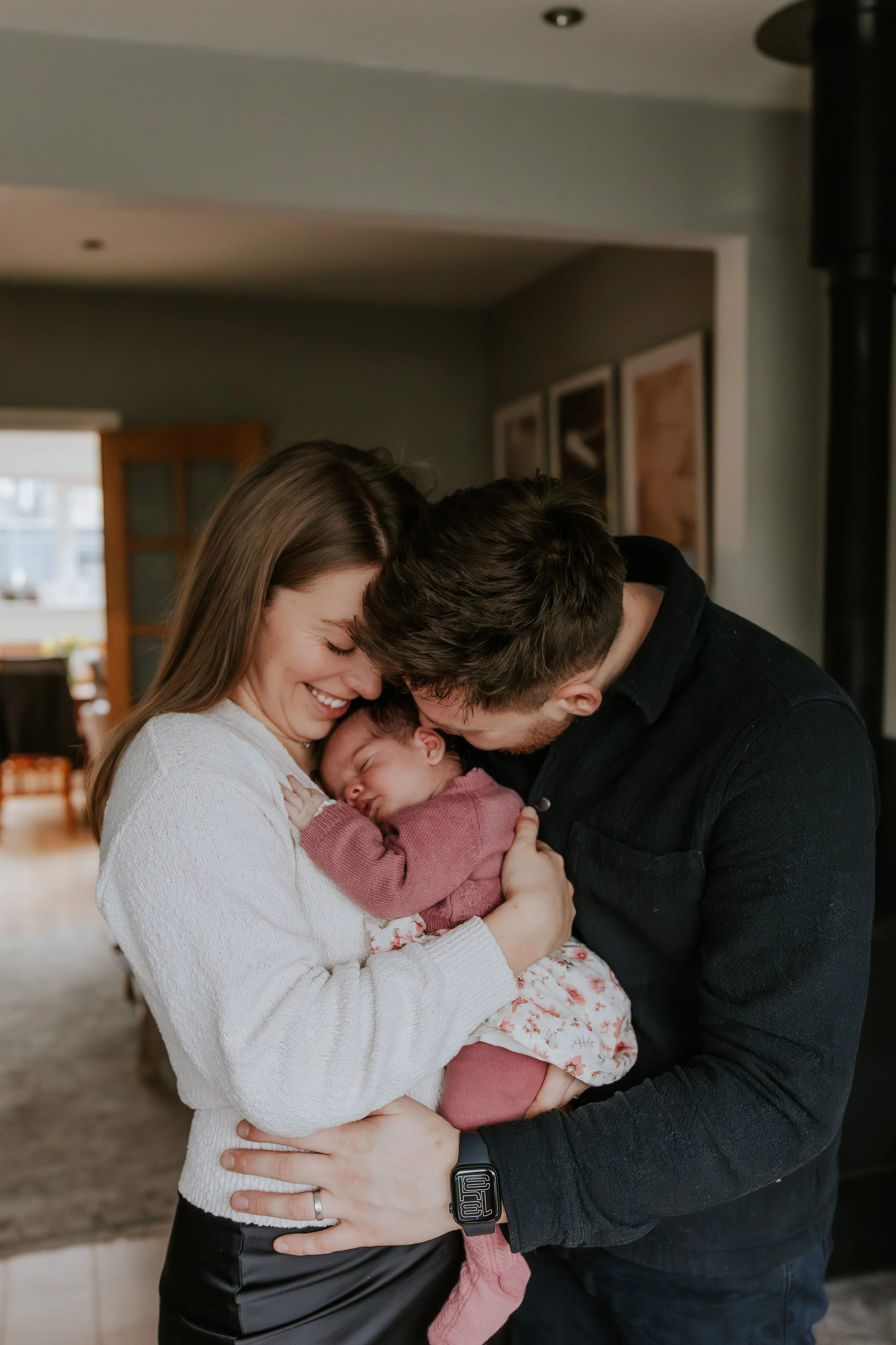 A happy family with a mother, father, and newborn baby sharing a joyful moment indoors.