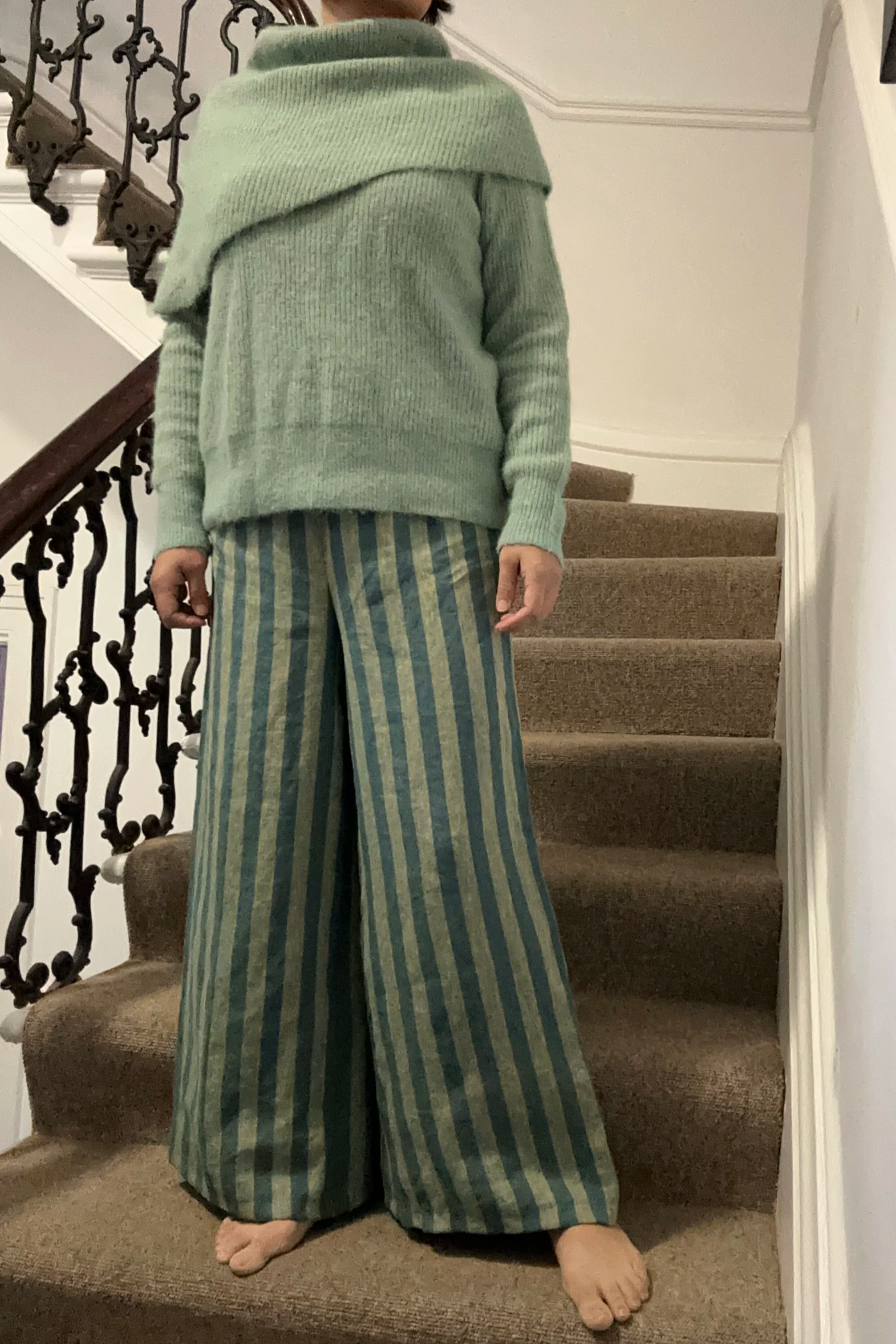 Adult wearing Wide Leg Linen Trousers – Sage & Teal Stripe, knitted light green jumper