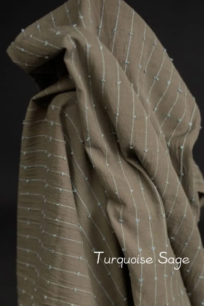 close up light cotton fabric: deep green-grey base with pale turquoise woven detail