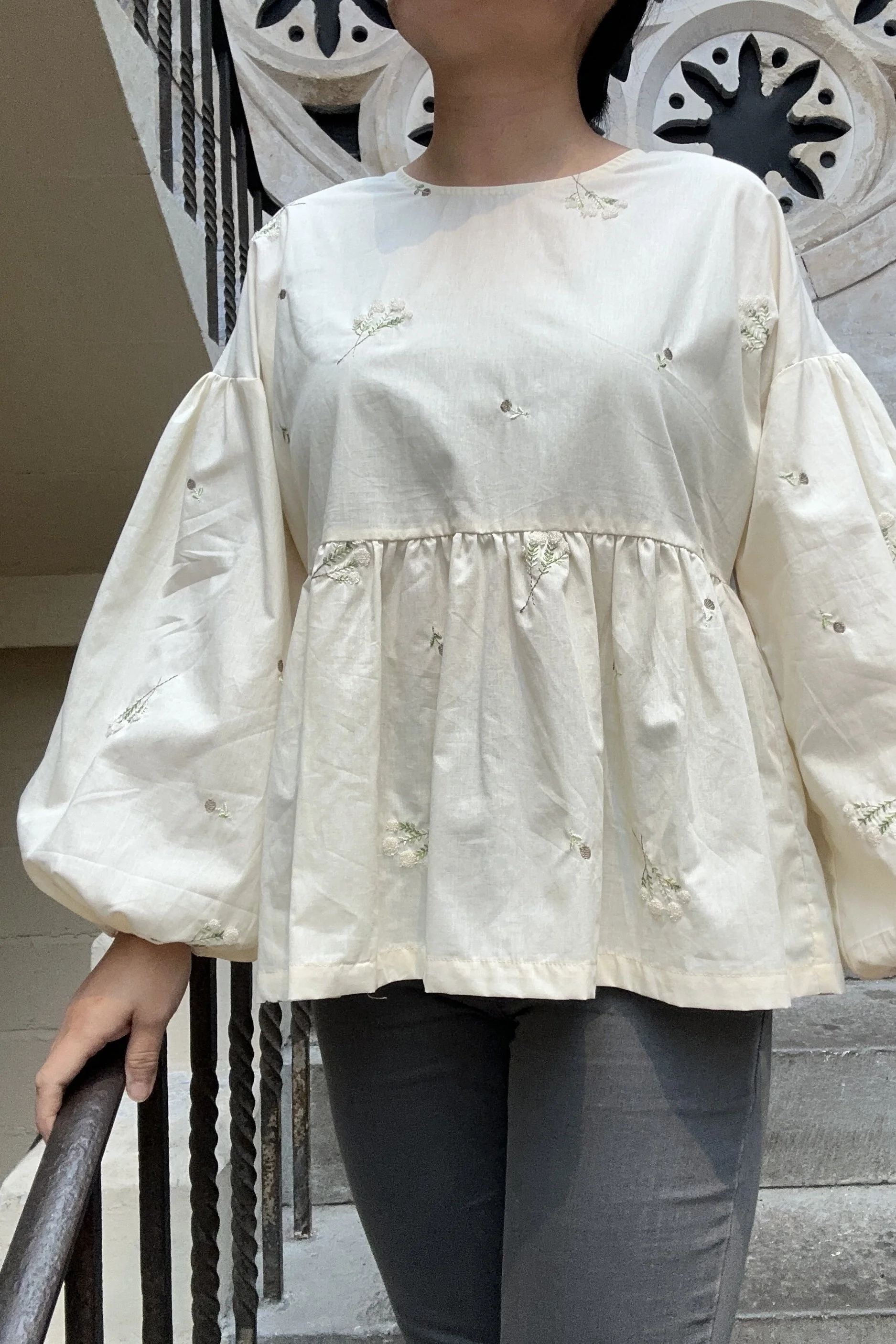 Adult wearing embroidered lace flower Top, Featuring a relaxed fit, balloon sleeves, paired with grey skinny jeans