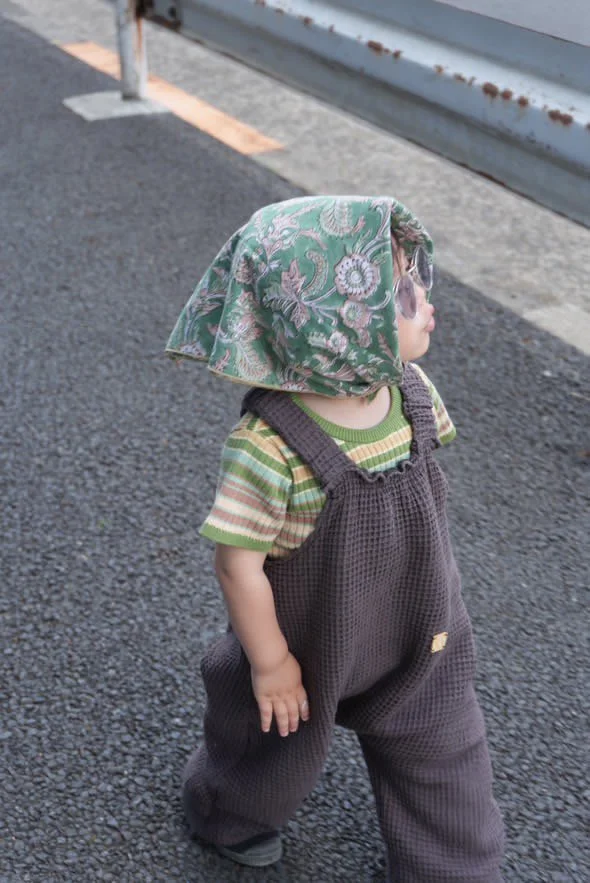 child wearing organic cotton waffle pullover dungarees charcoal layered with stripy t shirt, a floral handkerchief wrapped on head, and sun glasses