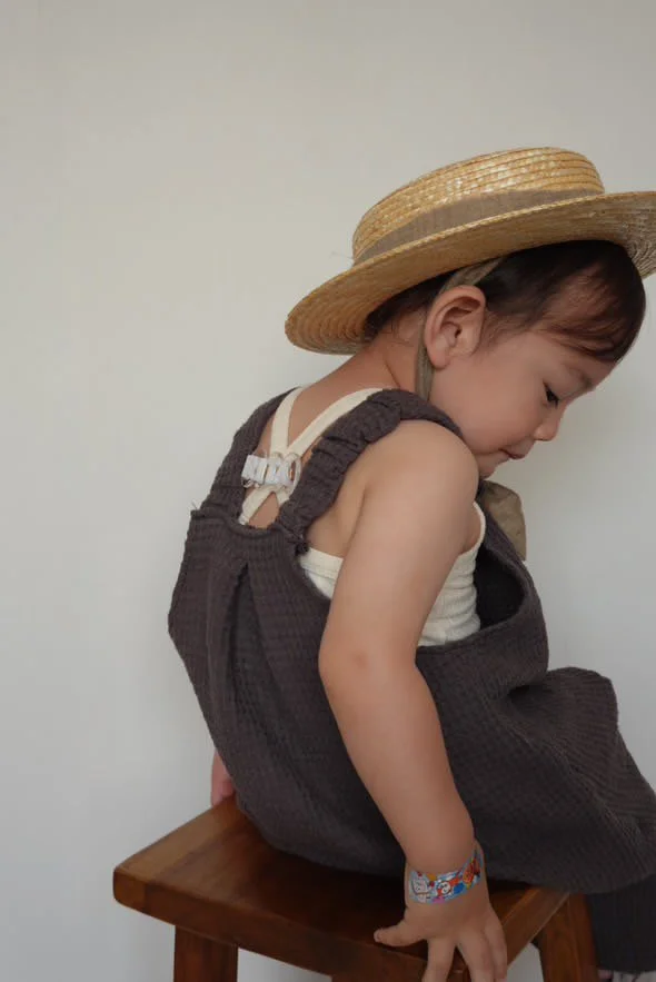 side view of child wearing organic cotton waffle pullover dungarees charcoal, sun hat