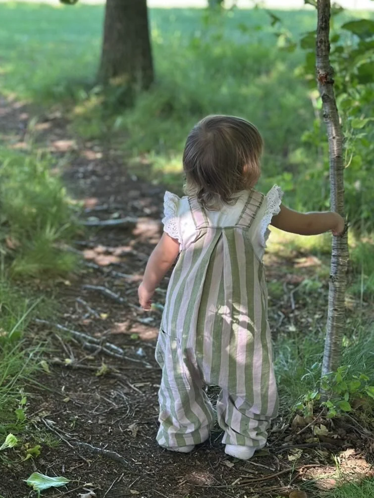 child wearing organic cotton linen stripe dungarees sage and lilac in the wood