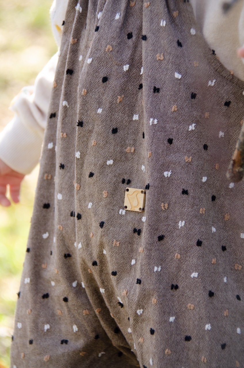close up child wearing organic cotton speckled cocoa dungarees, floral handkerchief,