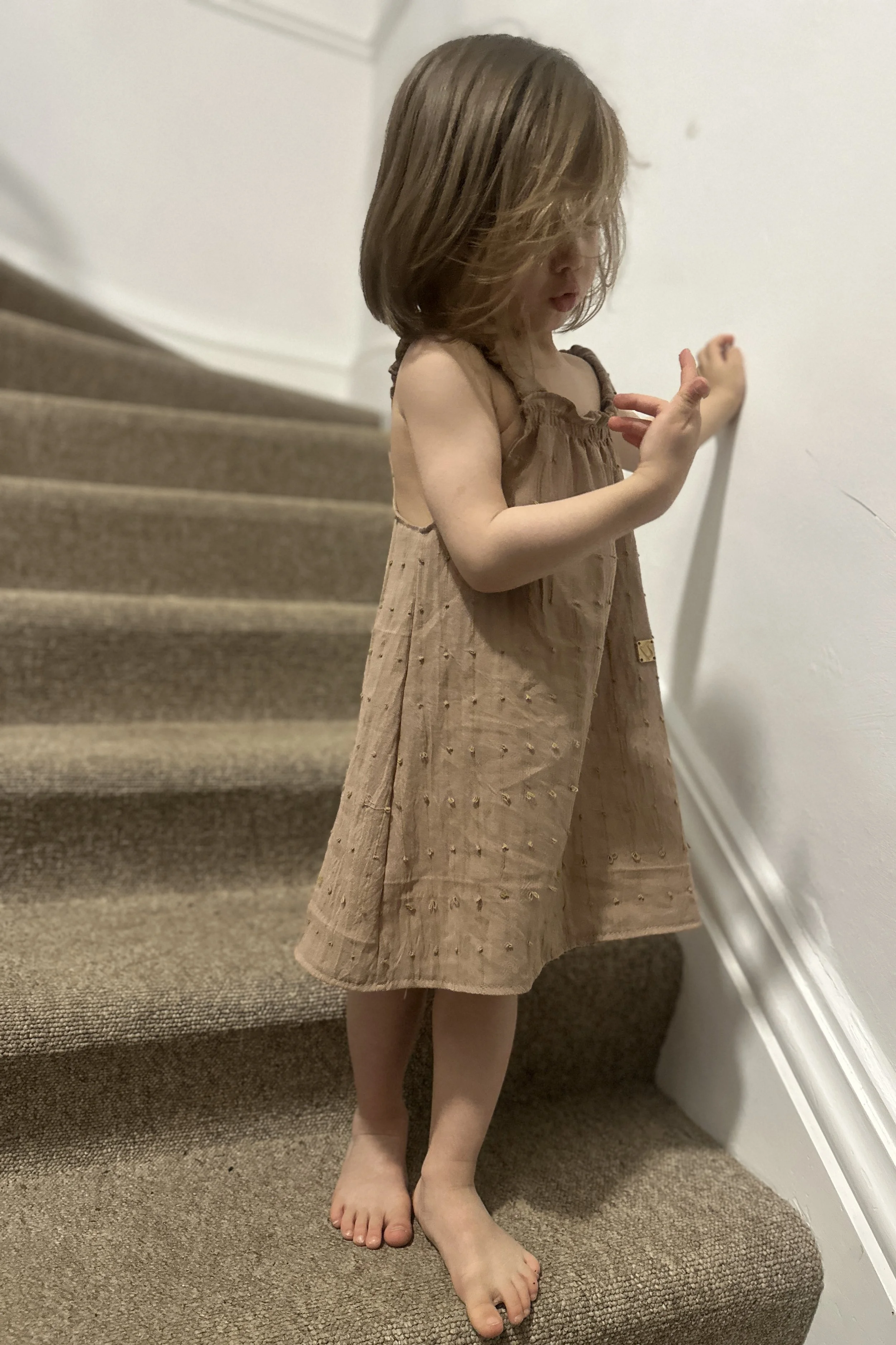 front view of child wearing summer dress made of light cotton soft pale pink woven with gentle yellow loops