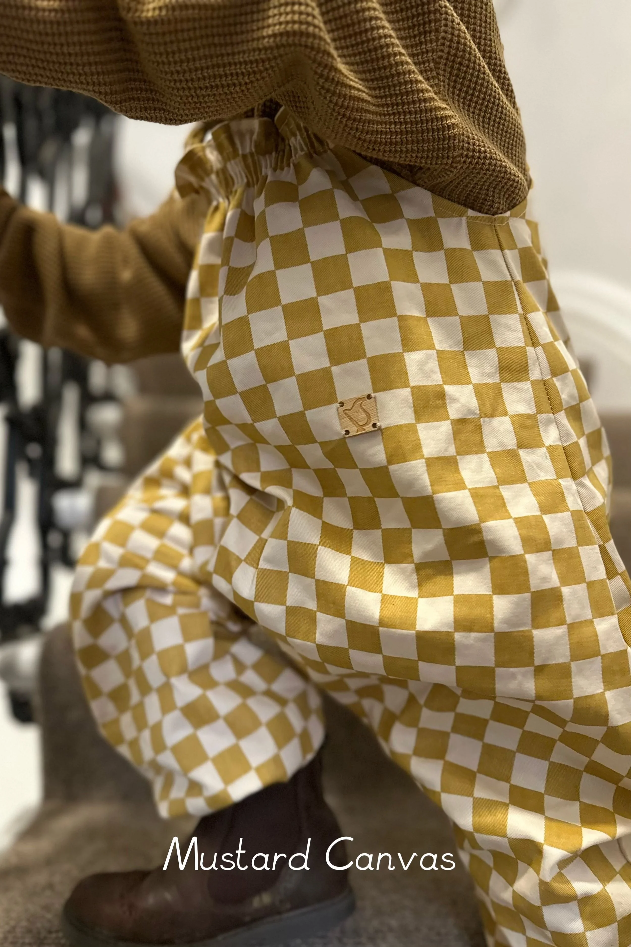 child wearing organic cotton pullover dungarees mustard checkerboard close up