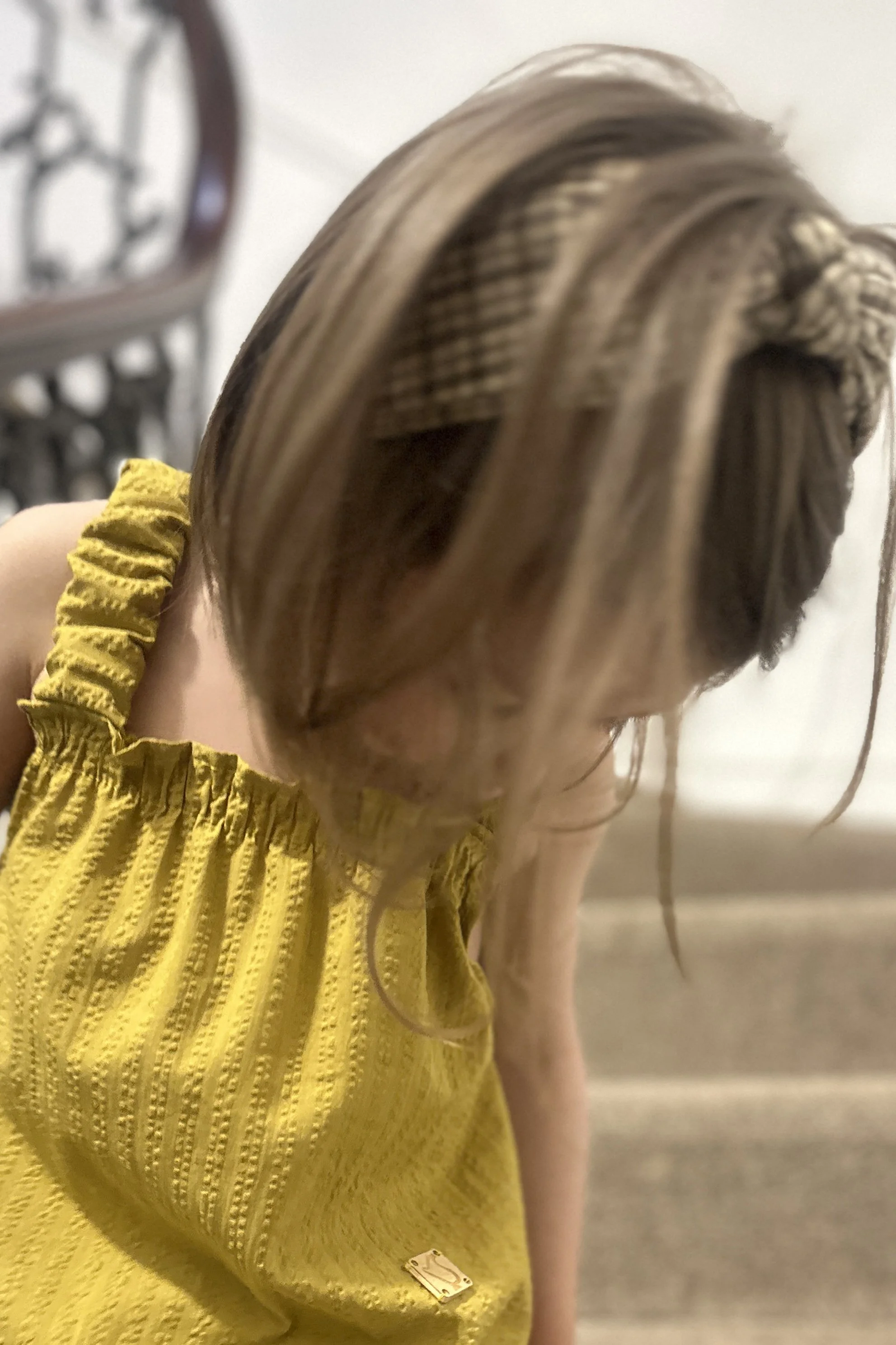 close up child wearing organic cotton seersucker stripe mustard dress standing on staircase
