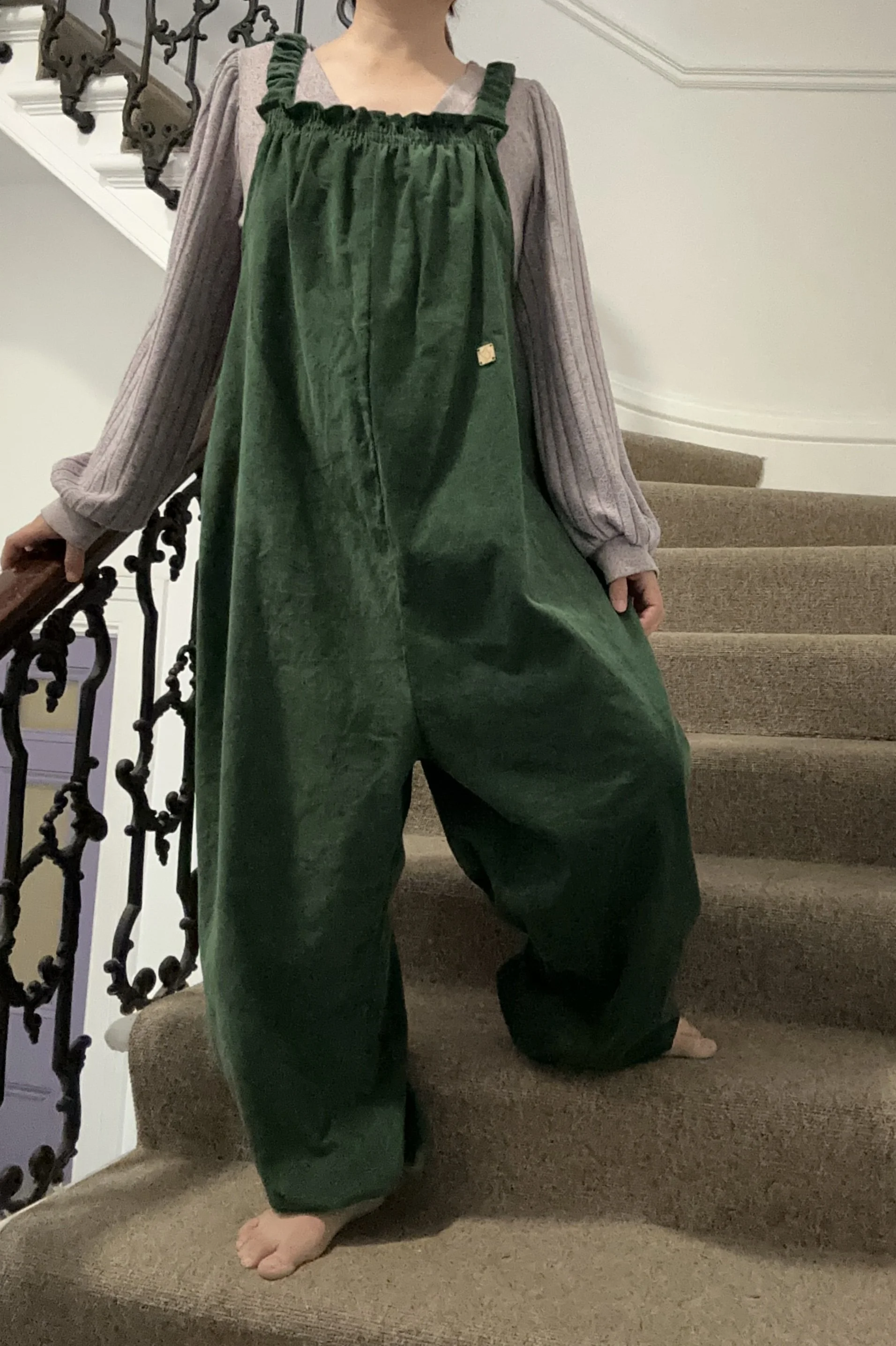 adult wearing organic cotton needlecord dungarees dark green, layered with lilac top