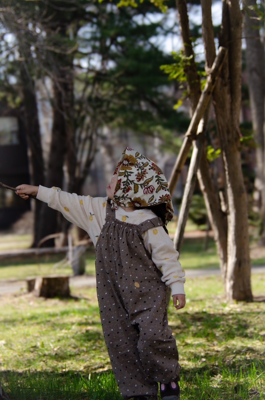child wearing organic cotton speckled cocoa dungarees, floral handkerchief,