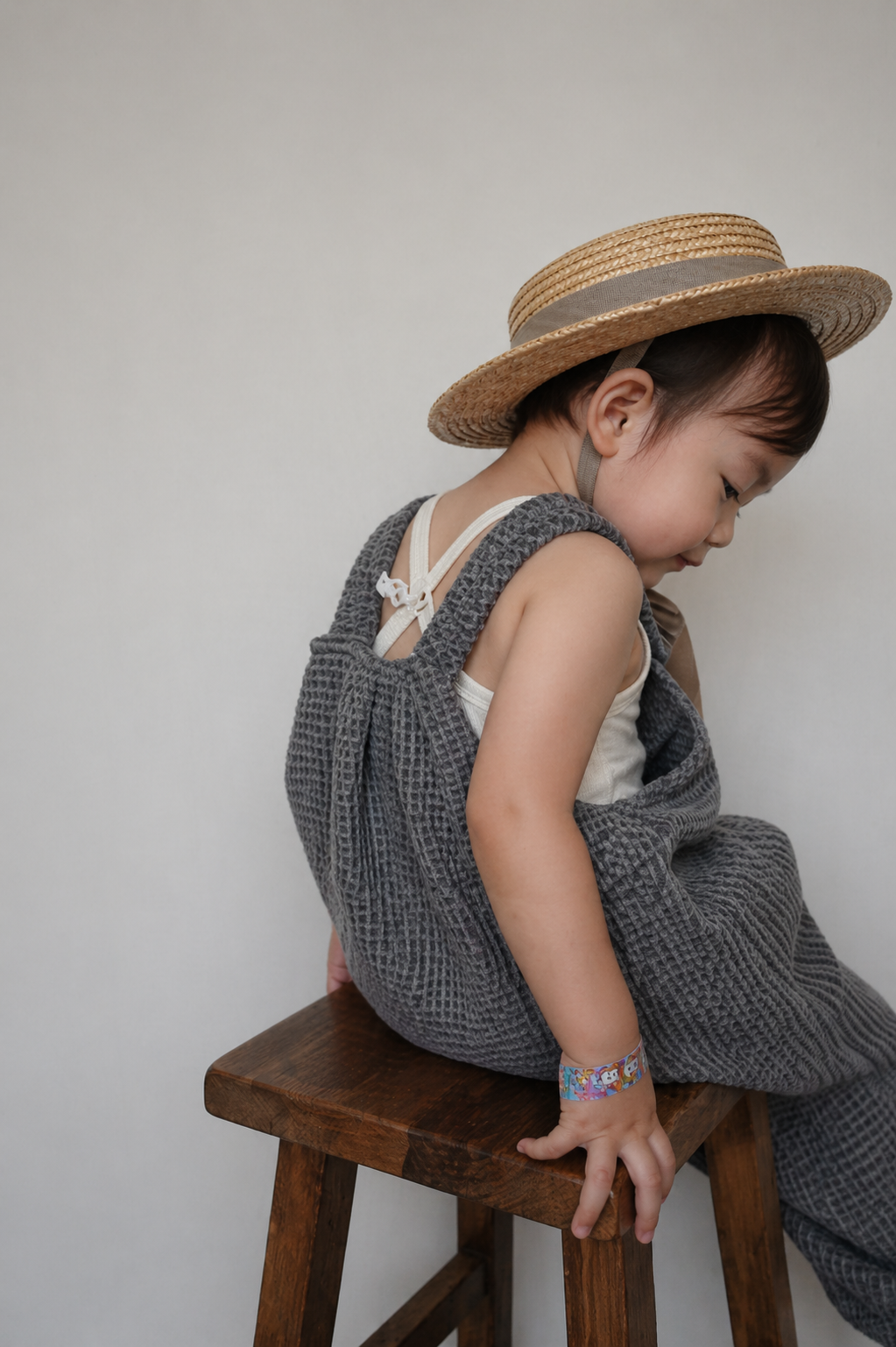 side view of child wearing organic cotton waffle pullover dungarees charcoal, sun hat