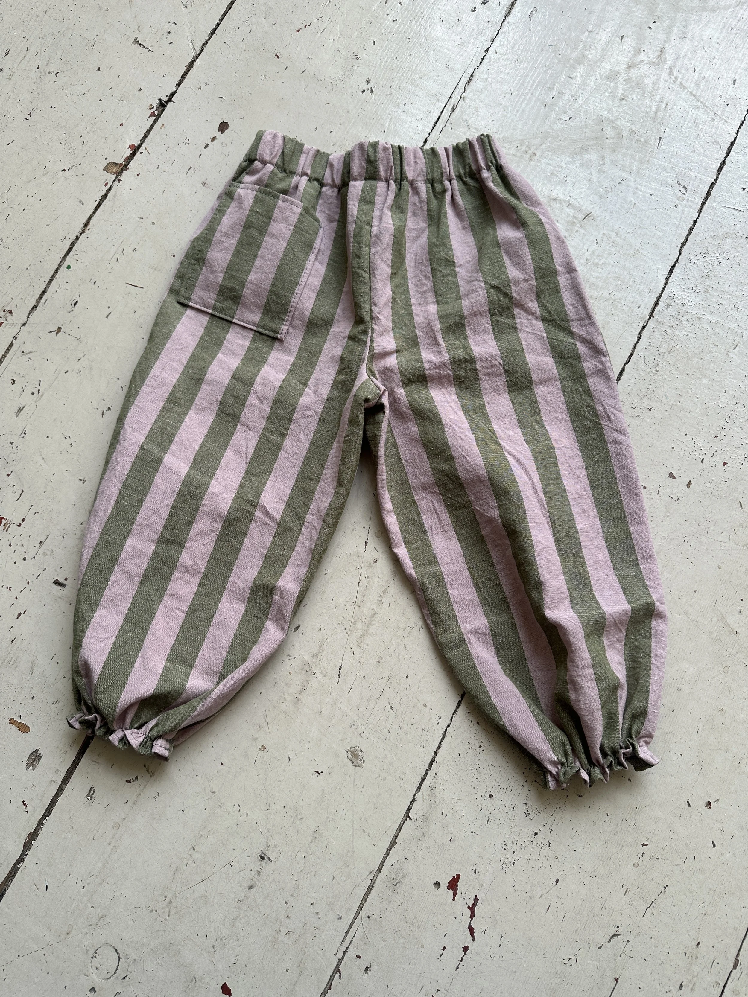 flatlay  back of organic cotton wide stripe barrel trousers in olive green and lilac colour, highlight pocket