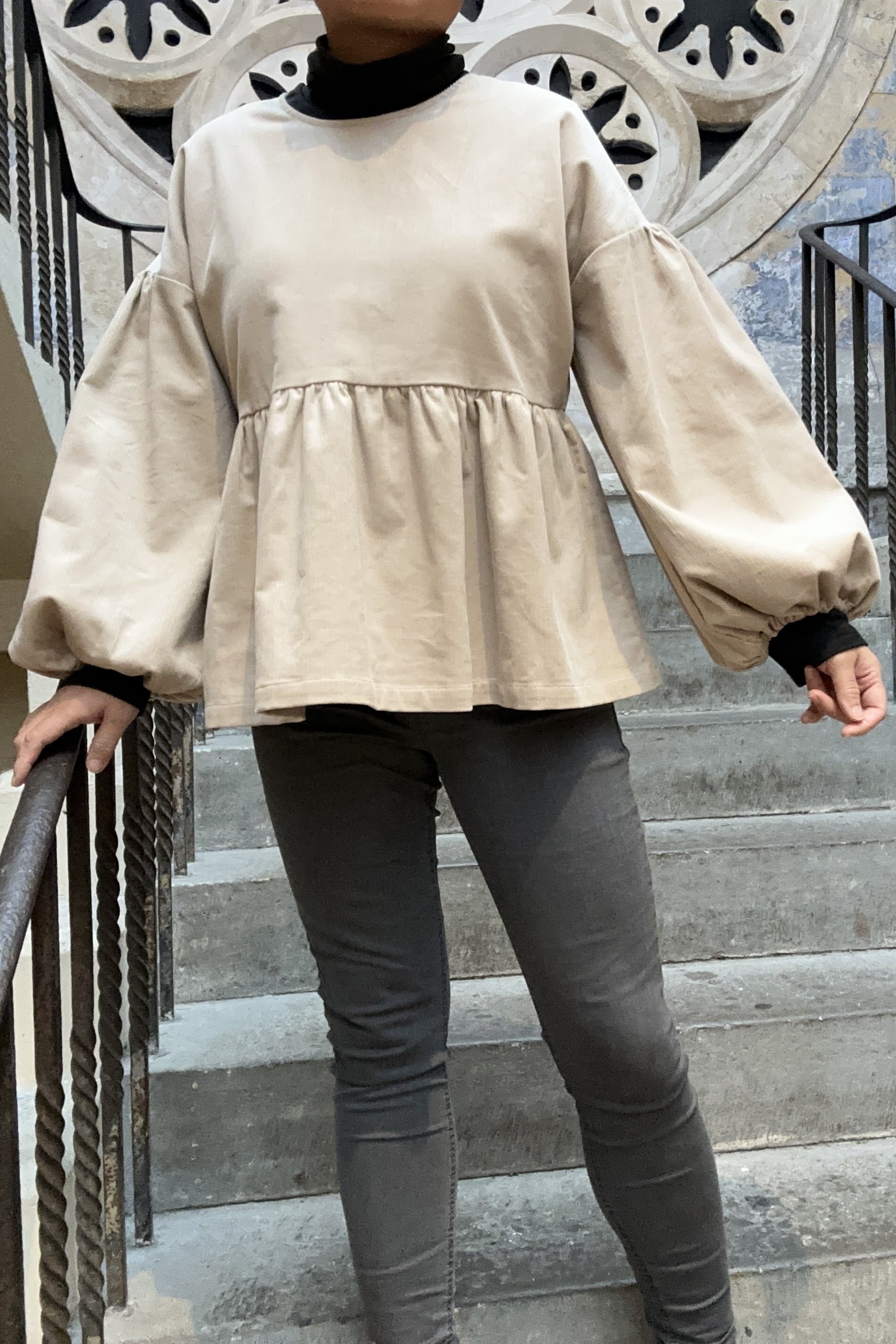Adult wearing Latte Corduroy Top, Featuring a relaxed fit, balloon sleeves, paired with grey skinny jeans