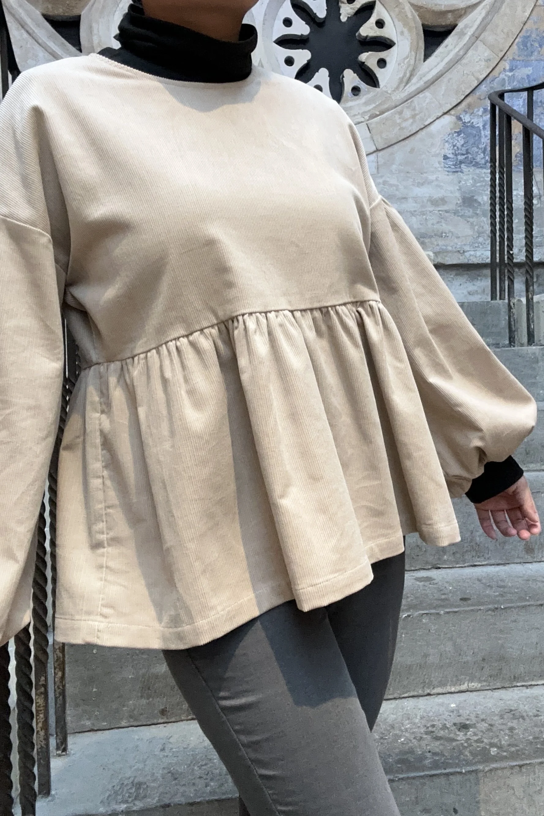 Adult wearing Latte Corduroy Top, Featuring a relaxed fit, balloon sleeves, paired with grey skinny jeans