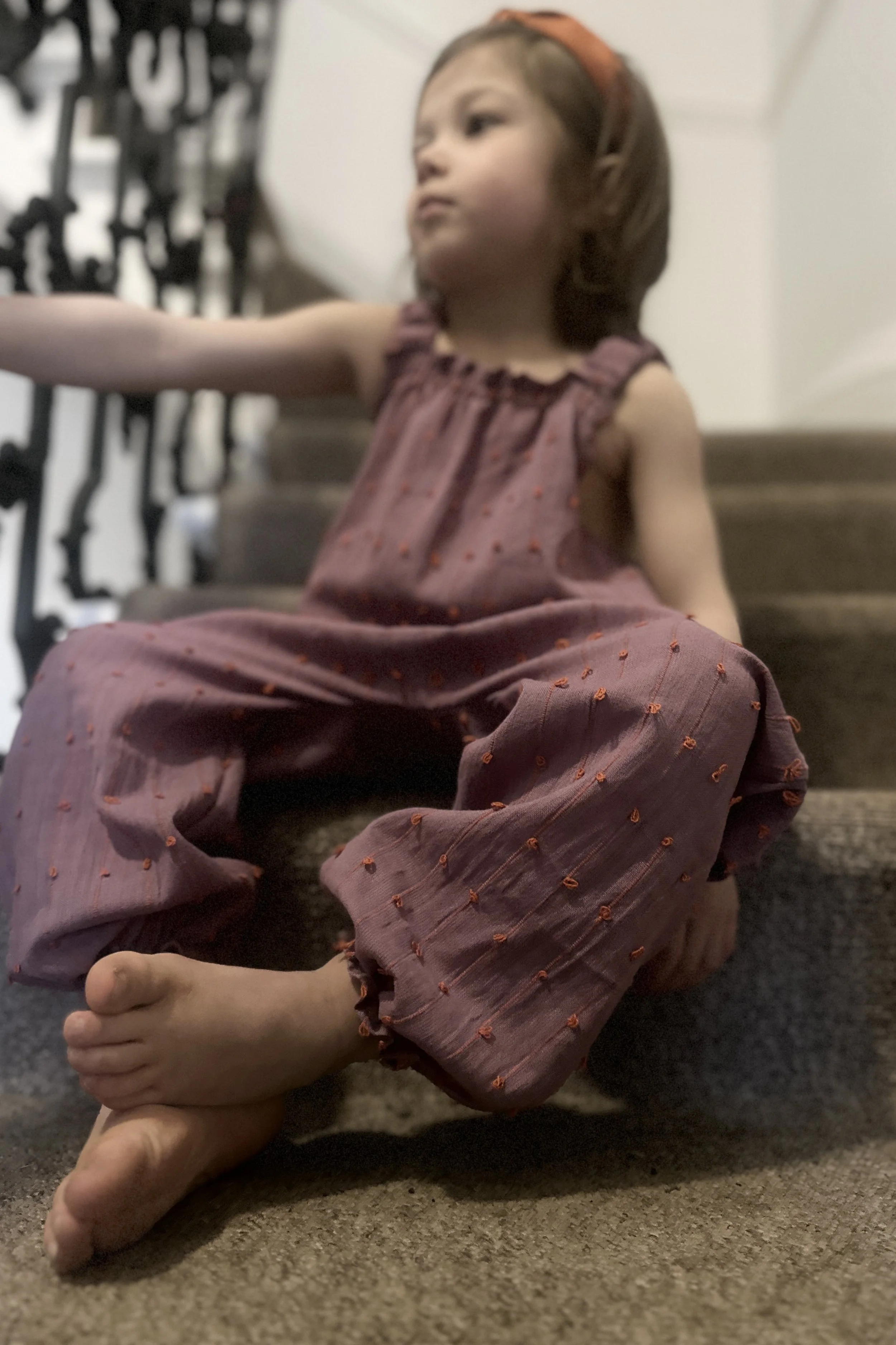 child wearing organic cotton loops dungarees berry blush colour standing on staircase
