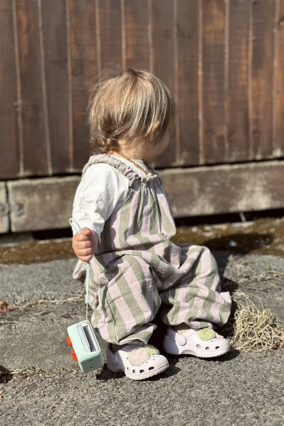 Toddler wearing organic cotton pullover dungarees sage and lilac stripes sitting down