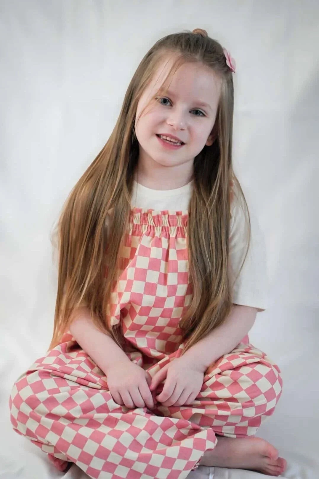 girl wearing organic cotton checkerboard dungarees in pink