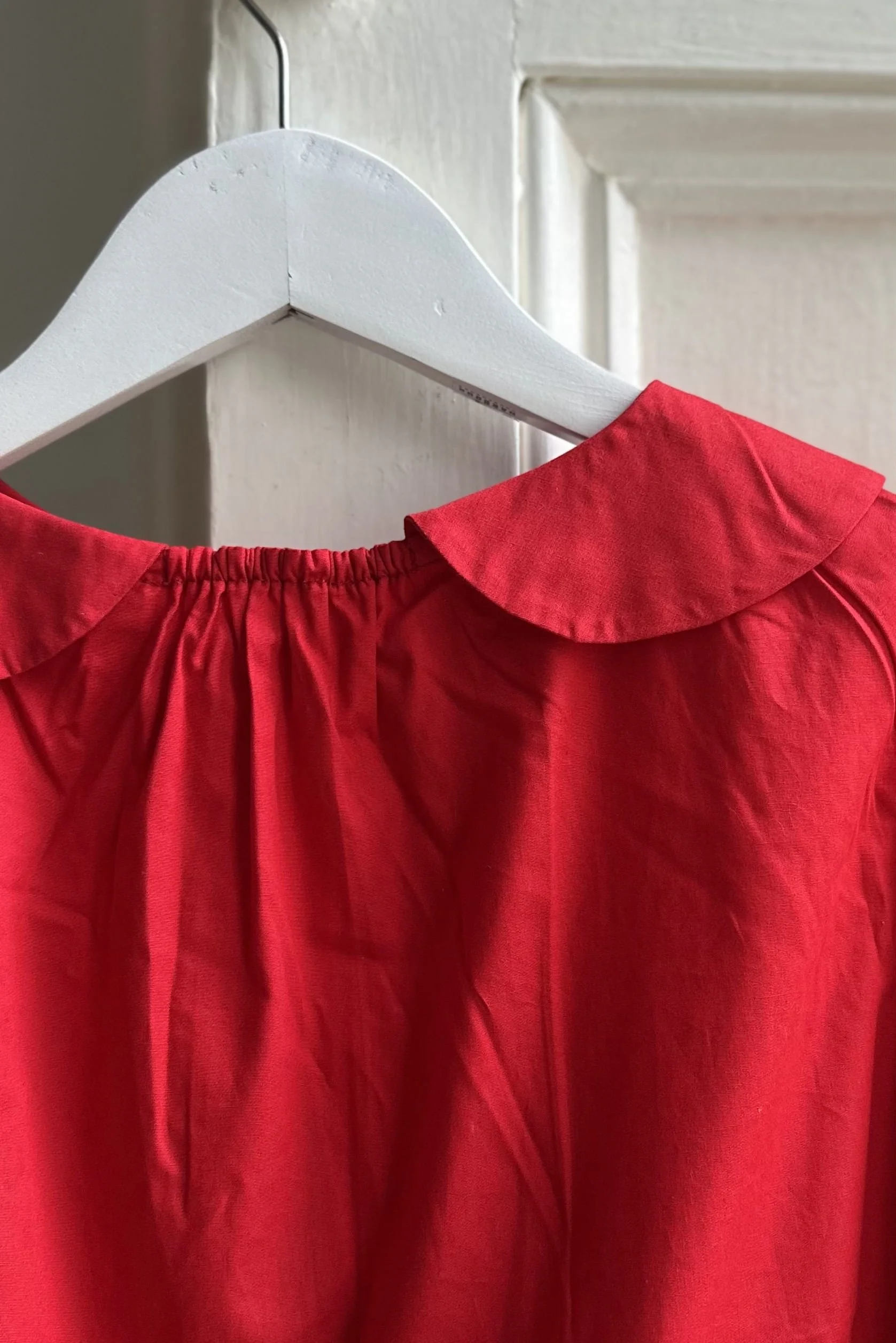 back of Hanging organic cotton red dress with Peter Pan Collar, highlighting elastic at neckline