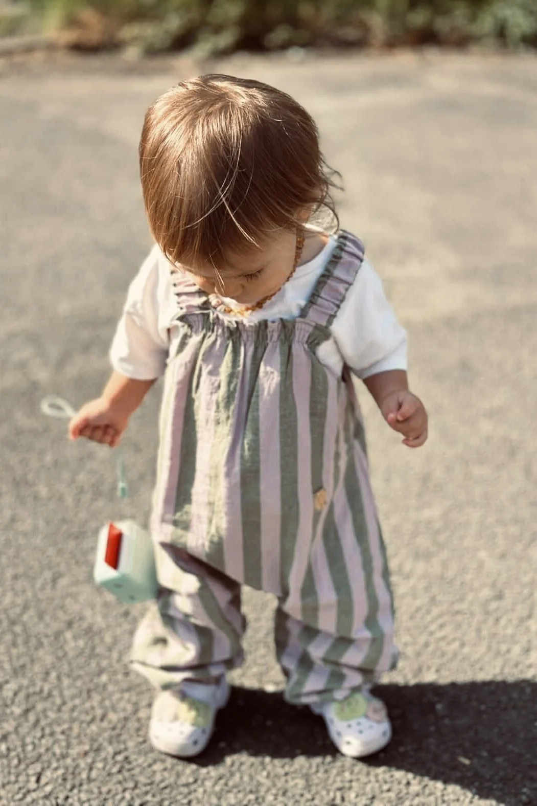 Toddler wearing organic cotton pullover dungarees sage and lilac stripes walking