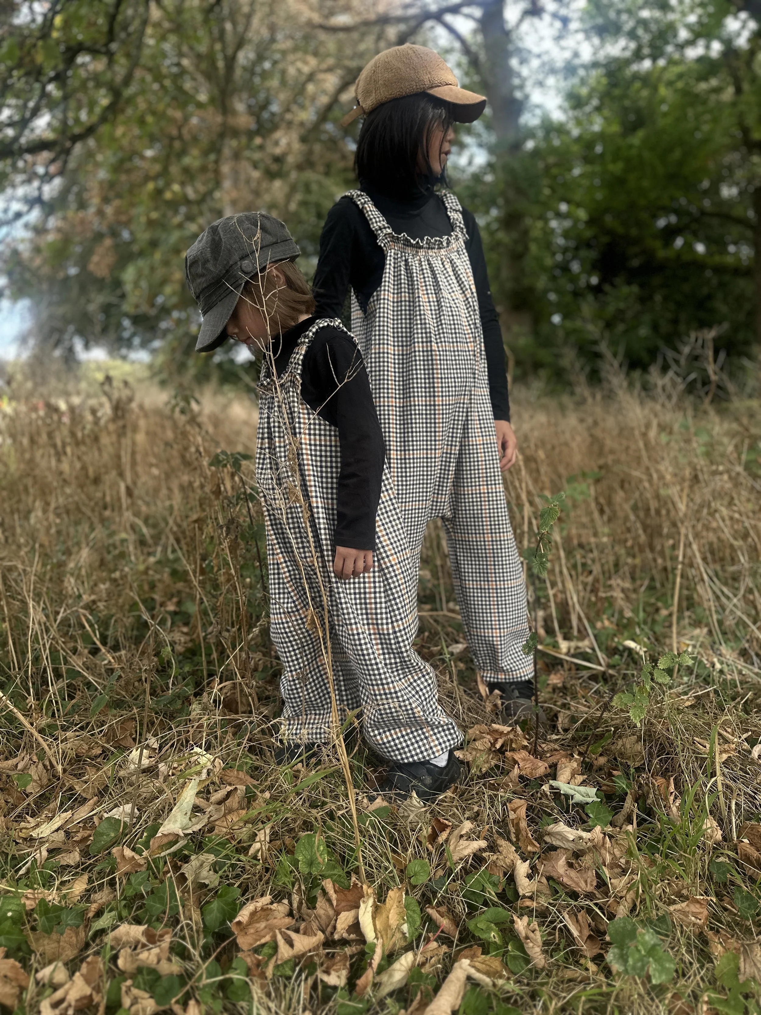 a child and an adult wearing organic cotton retro brown check dungarees layered with black top