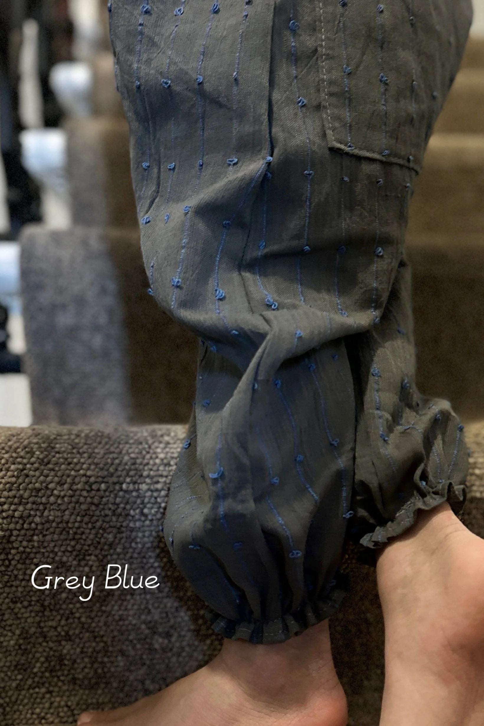 close up elastic hem child wearing organic cotton loops dungarees grey blue colour standing on staircase