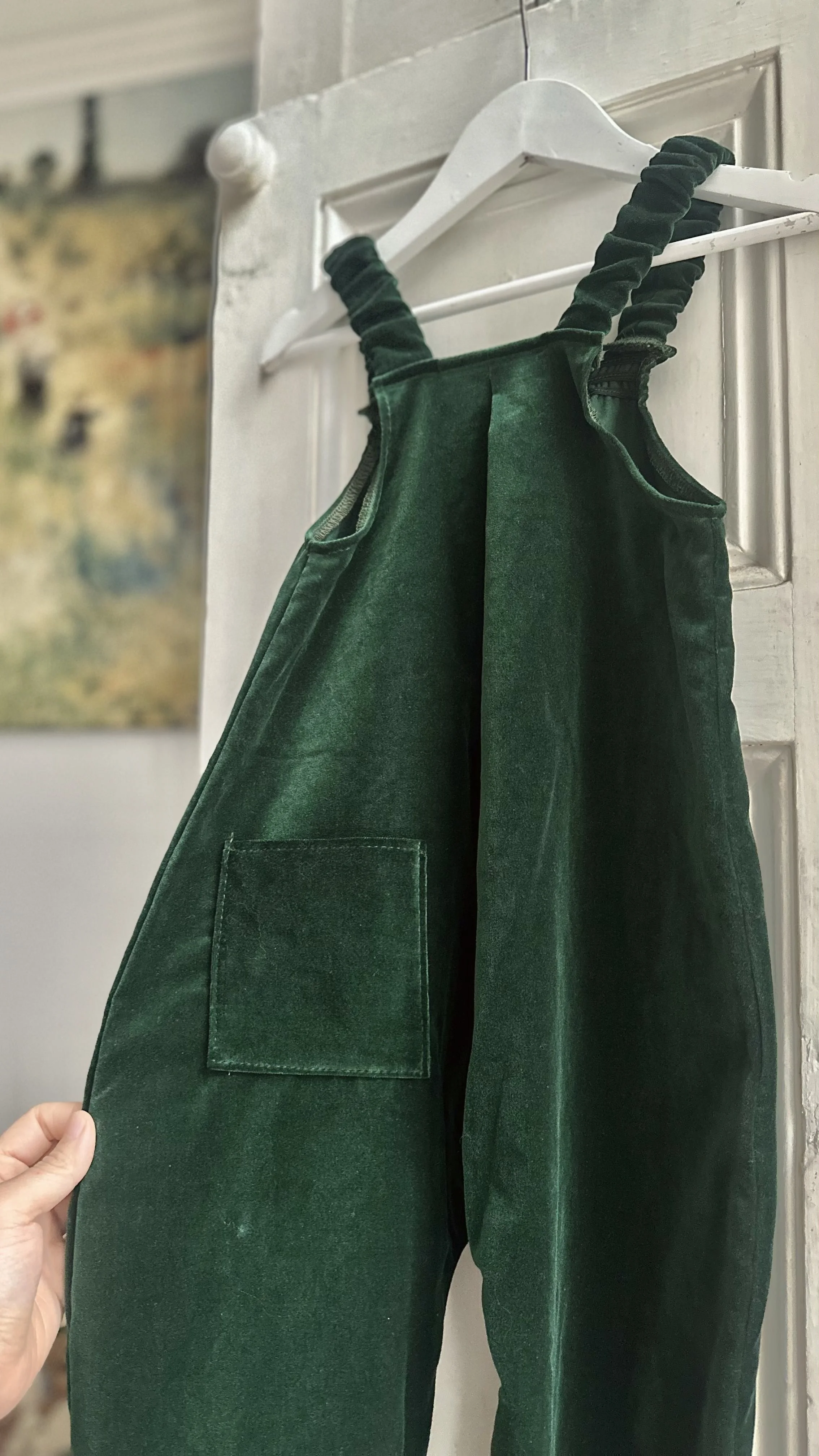 flatlay back of dark green organic velvet pullover dungarees highlighting pocket