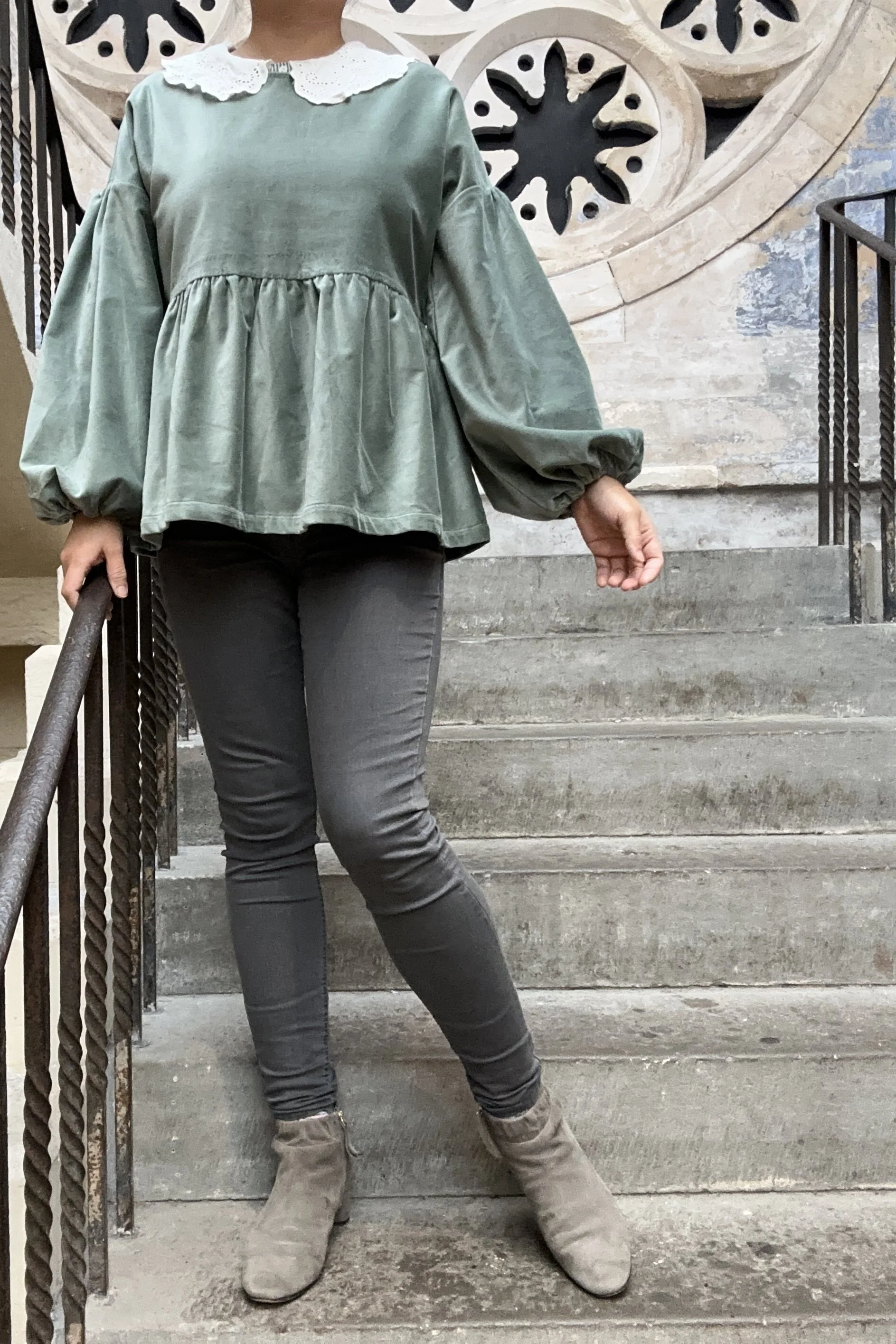 Adult wearing duck egg green-grey velvet Top, Featuring a relaxed fit, balloon sleeves, paired with grey skinny jeans, and grey boots