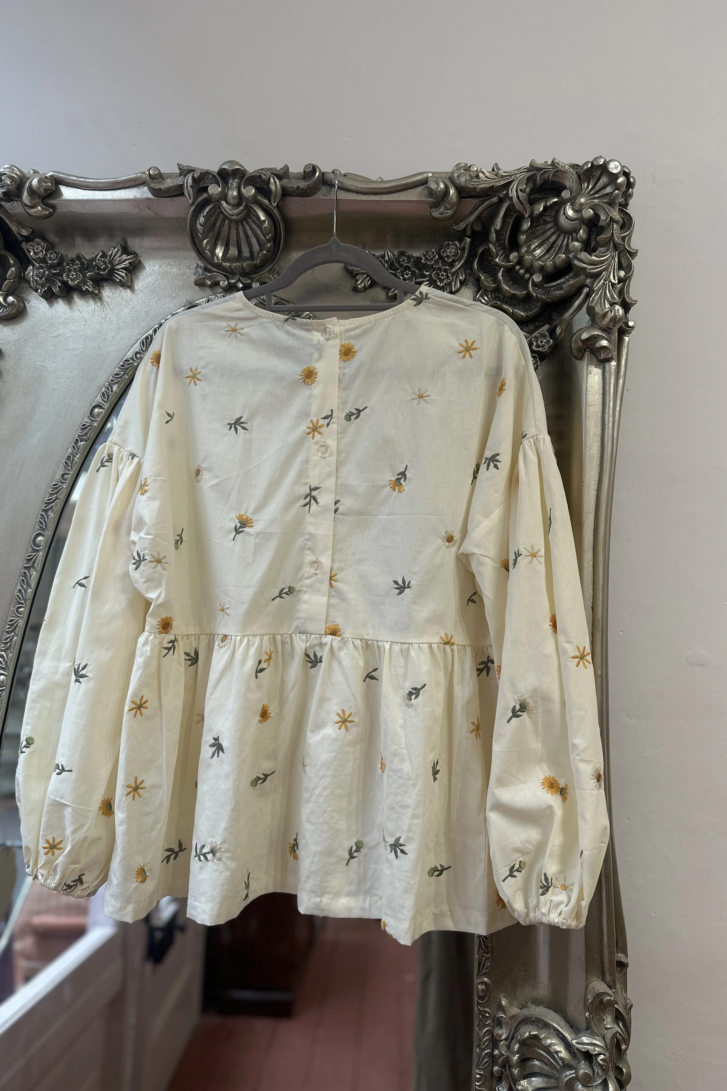 back view of hanging embroidered dandelions Top, Featuring a relaxed fit, balloon sleeves, a statement line of buttons