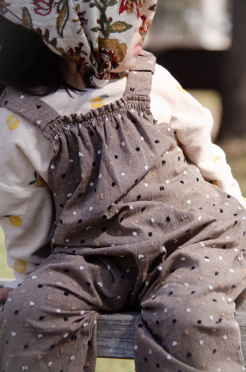 close up fabric details, child wearing organic cotton speckled cocoa dungarees, floral handkerchief,