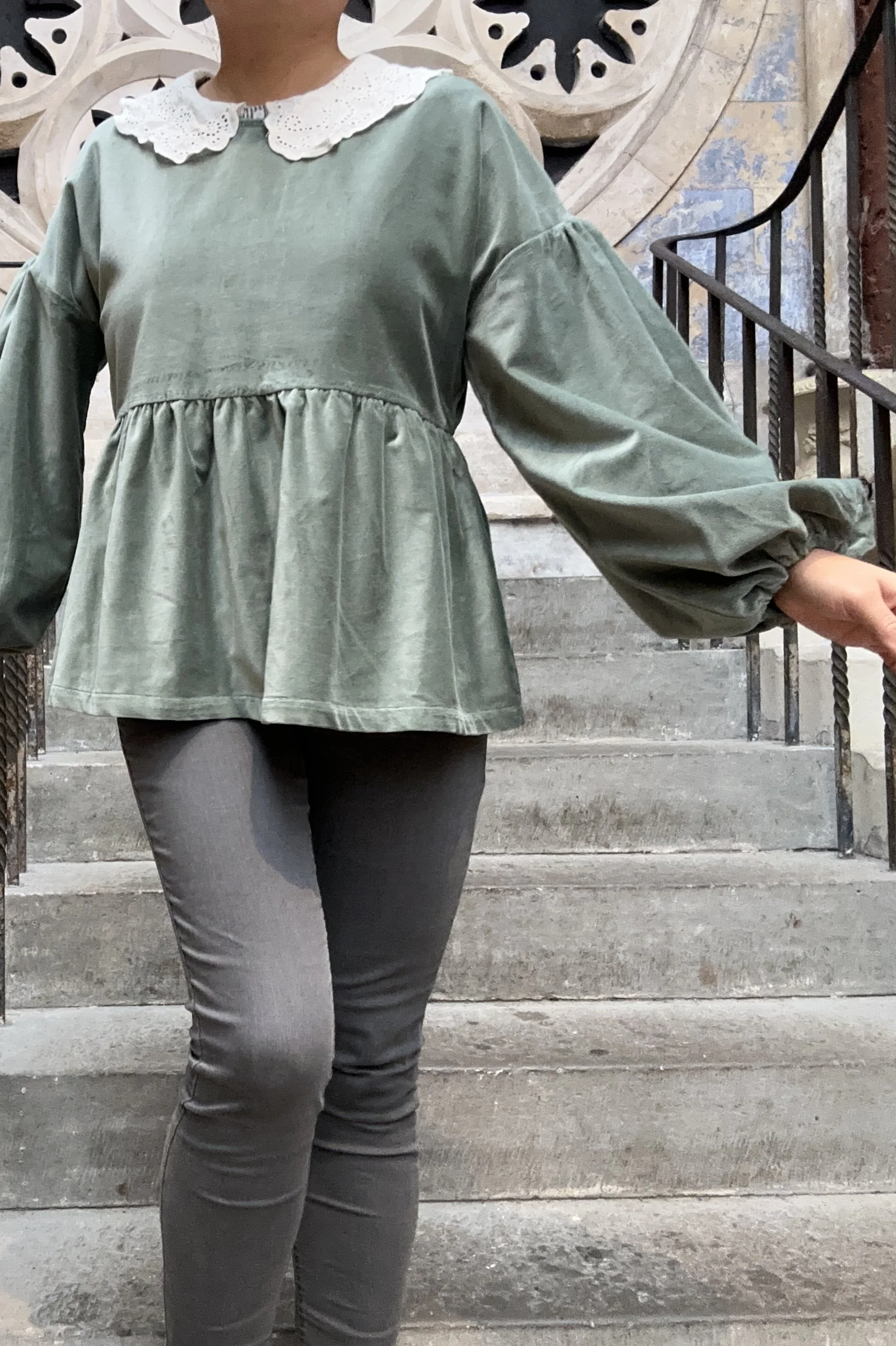 Adult wearing duck egg green-grey velvet Top, Featuring a relaxed fit, balloon sleeves, paired with grey skinny jeans, and grey boots