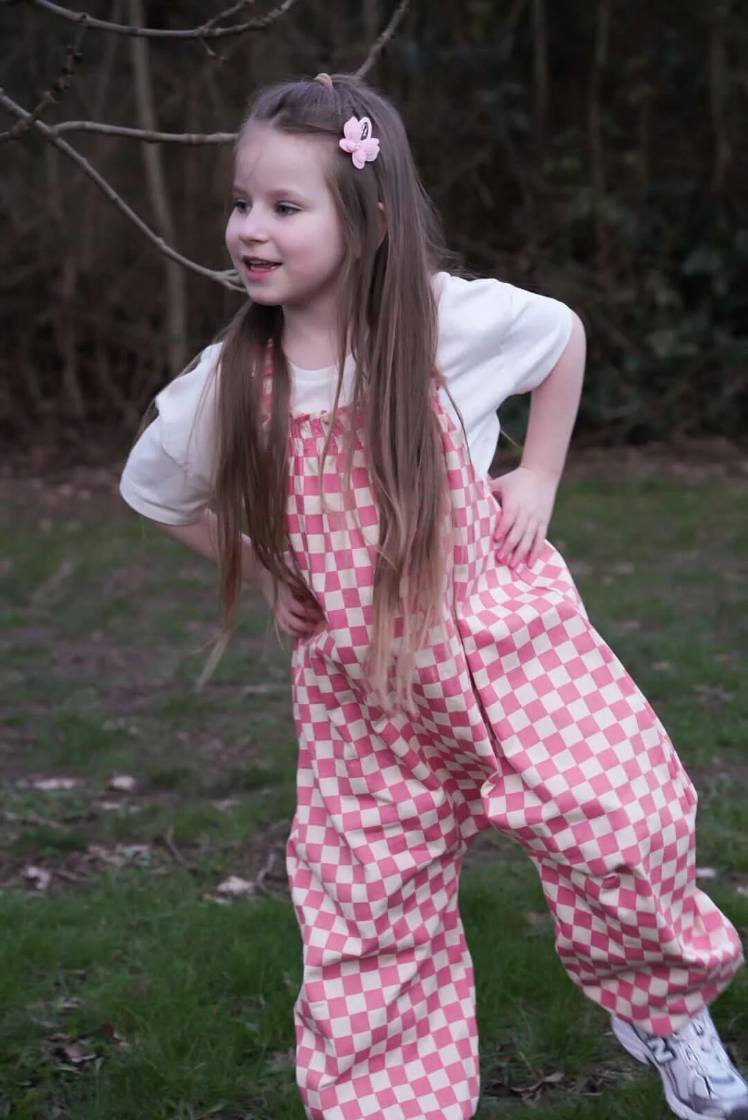 girl wearing organic cotton checkerboard dungarees in pink