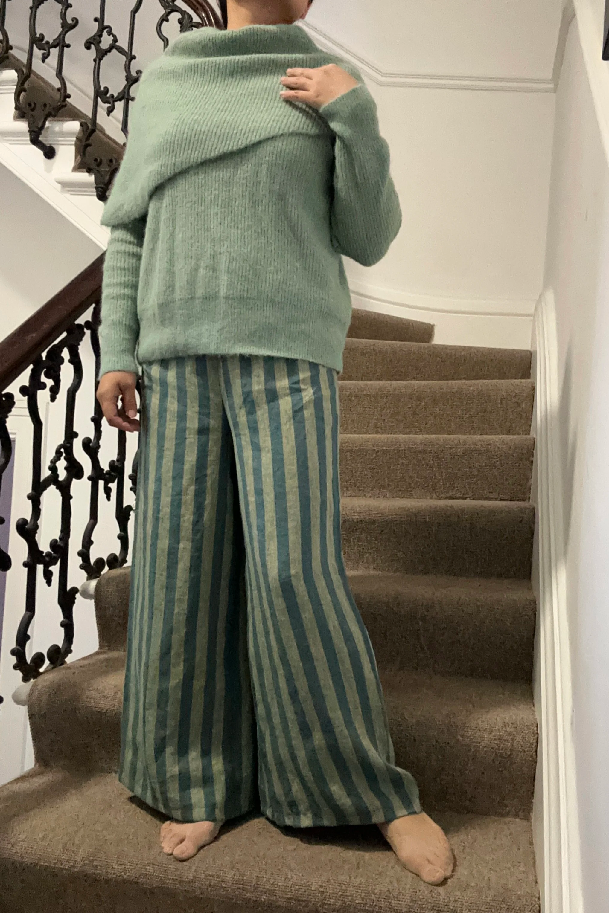 Adult wearing Wide Leg Linen Trousers – Sage & Teal Stripe, knitted light green jumper
