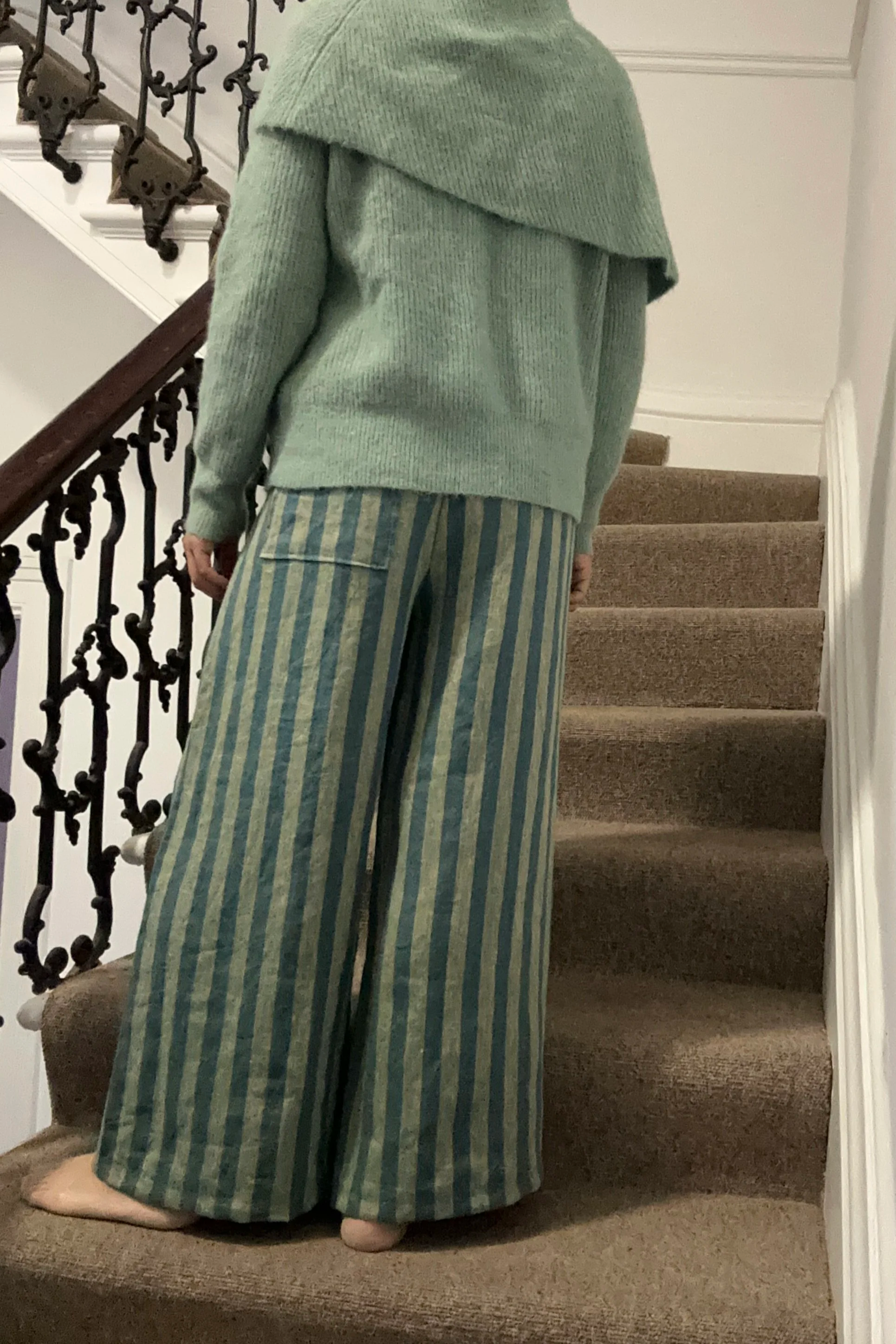 back view of Adult wearing Wide Leg Linen Trousers – Sage & Teal Stripe, knitted light green jumper