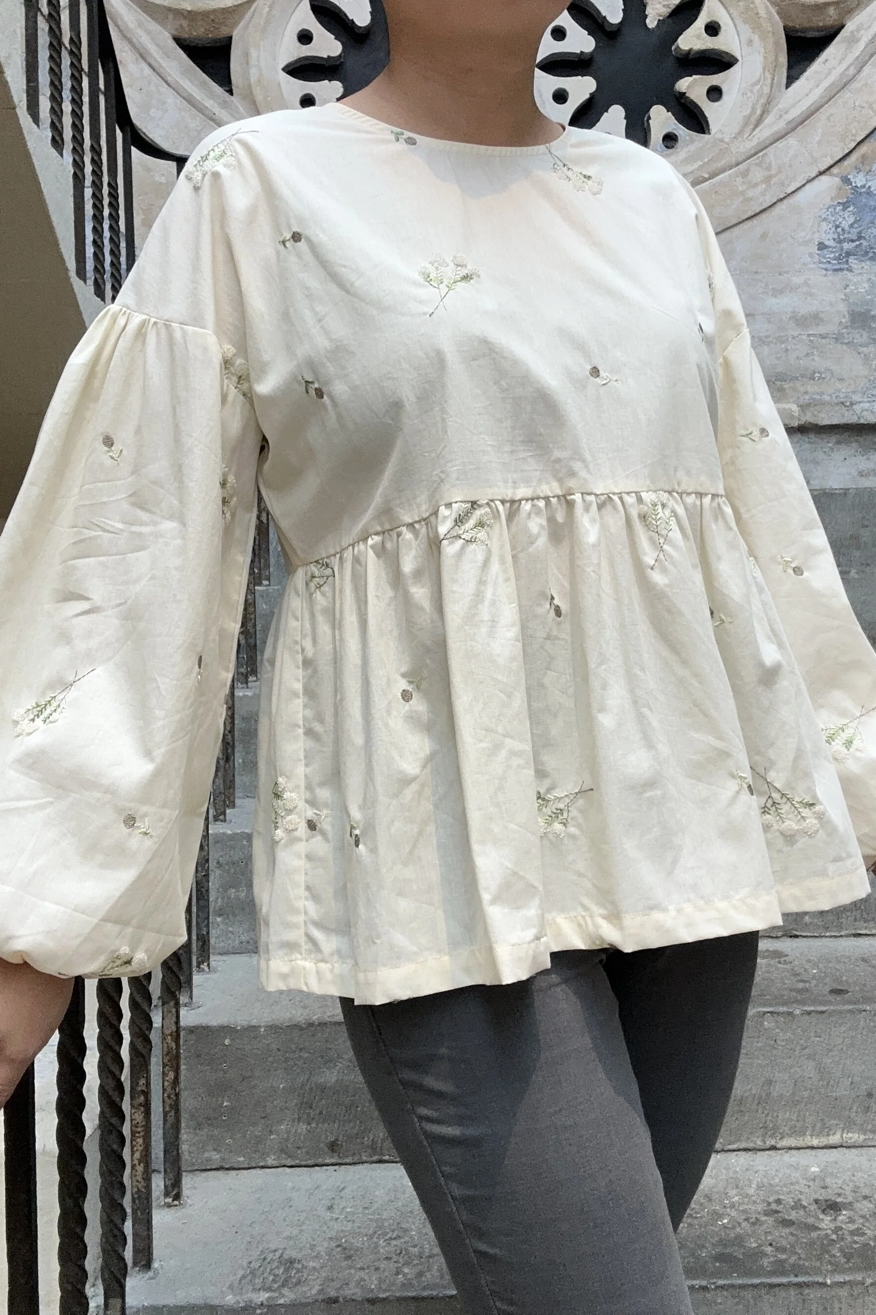 Adult wearing embroidered lace flower Top, Featuring a relaxed fit, balloon sleeves, paired with grey skinny jeans