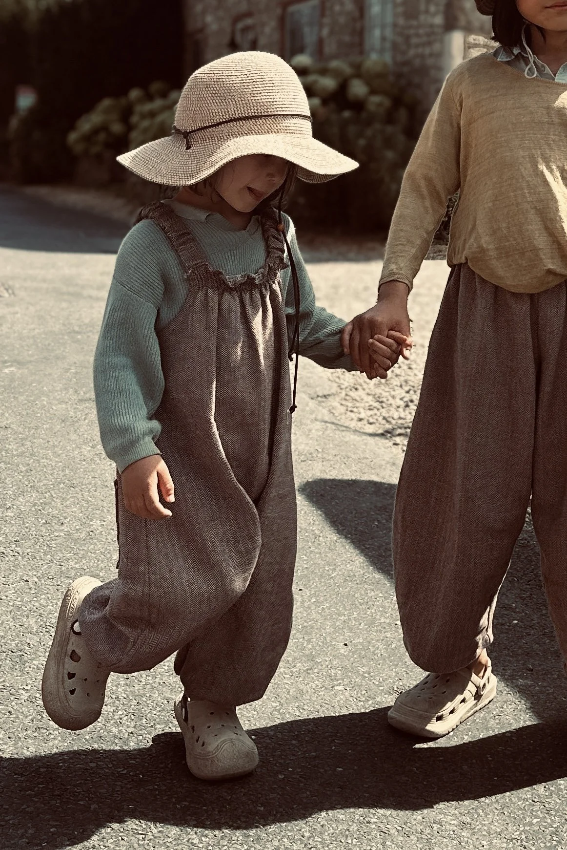 child wearing organic cotton herringbone brown dungarees layered with sage green jumper