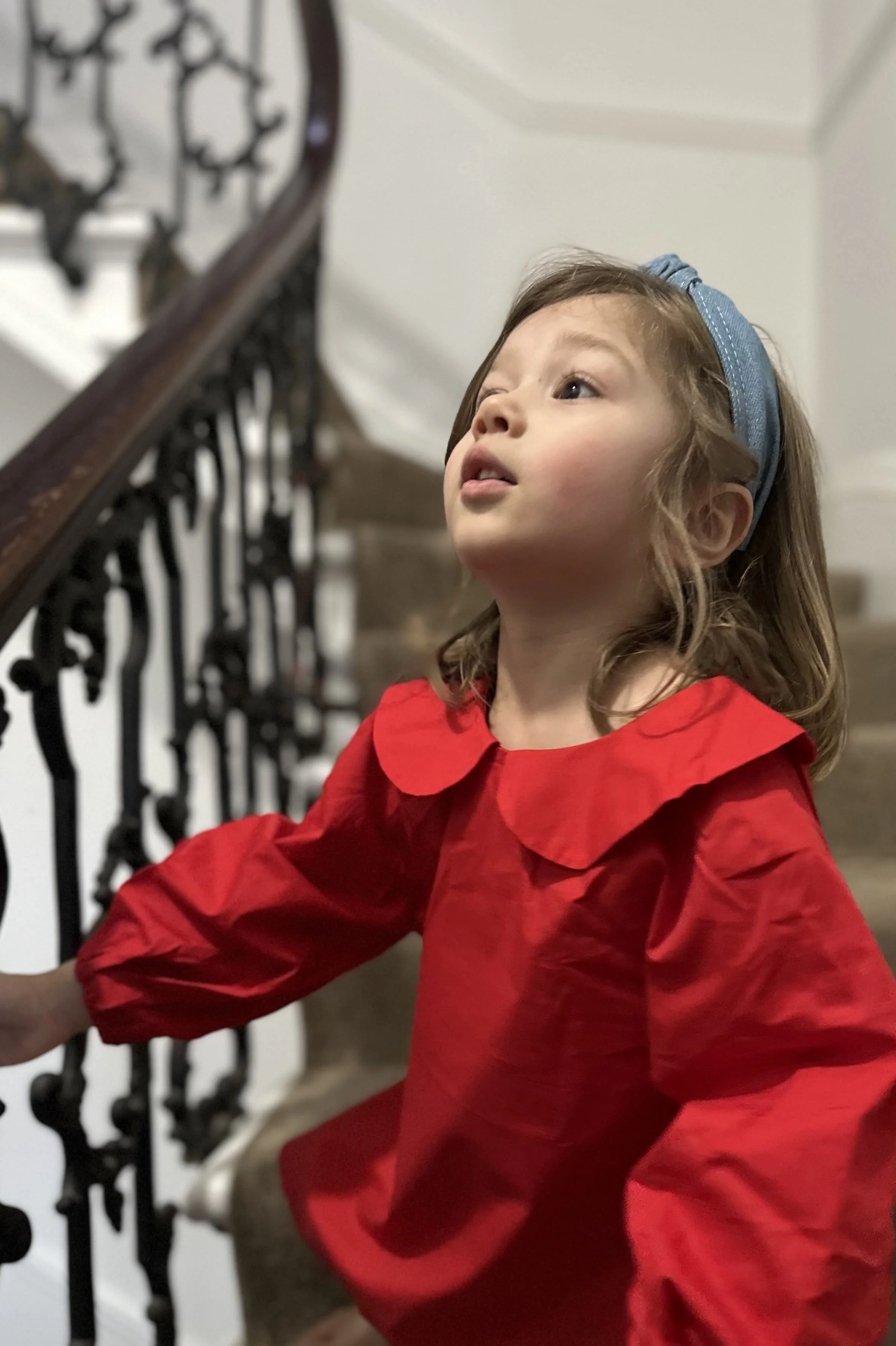 Close up Child wearing organic cotton red dress with Peter Pan Collar, denim blue headband, highlighting Peter Pan collar