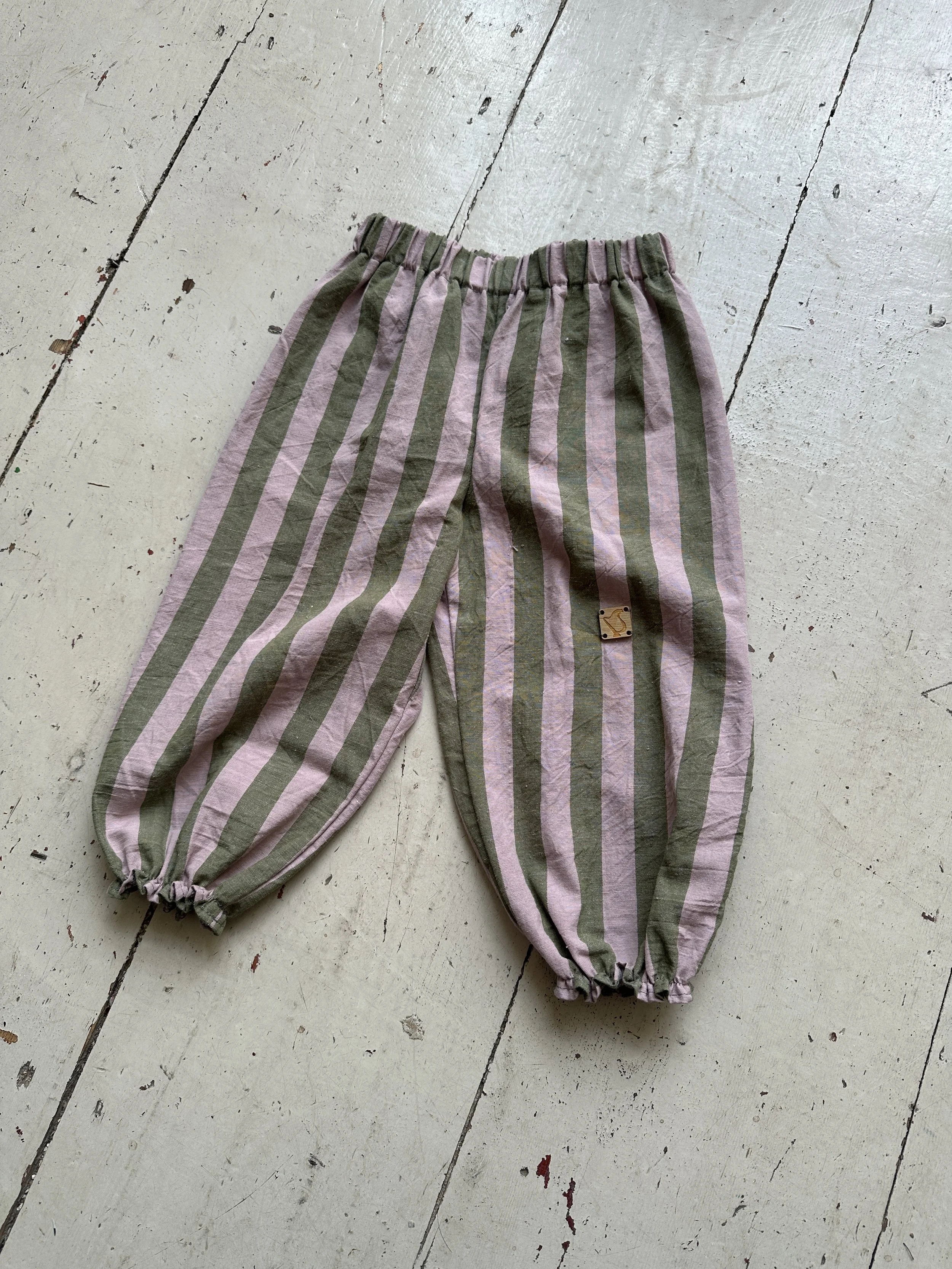 flatlay organic cotton wide stripe barrel trousers in olive green and lilac colour