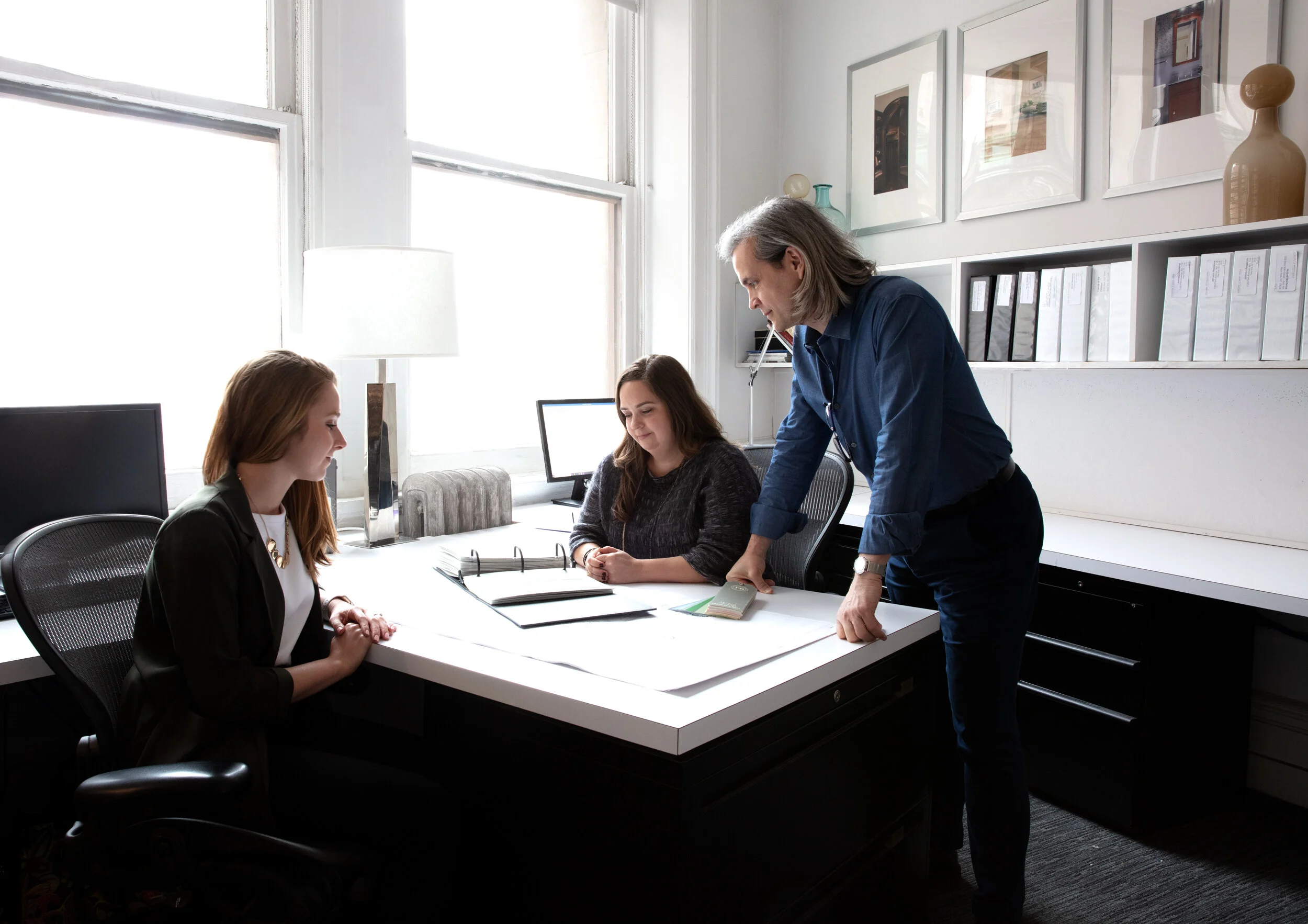 studio members at desk looking at binder