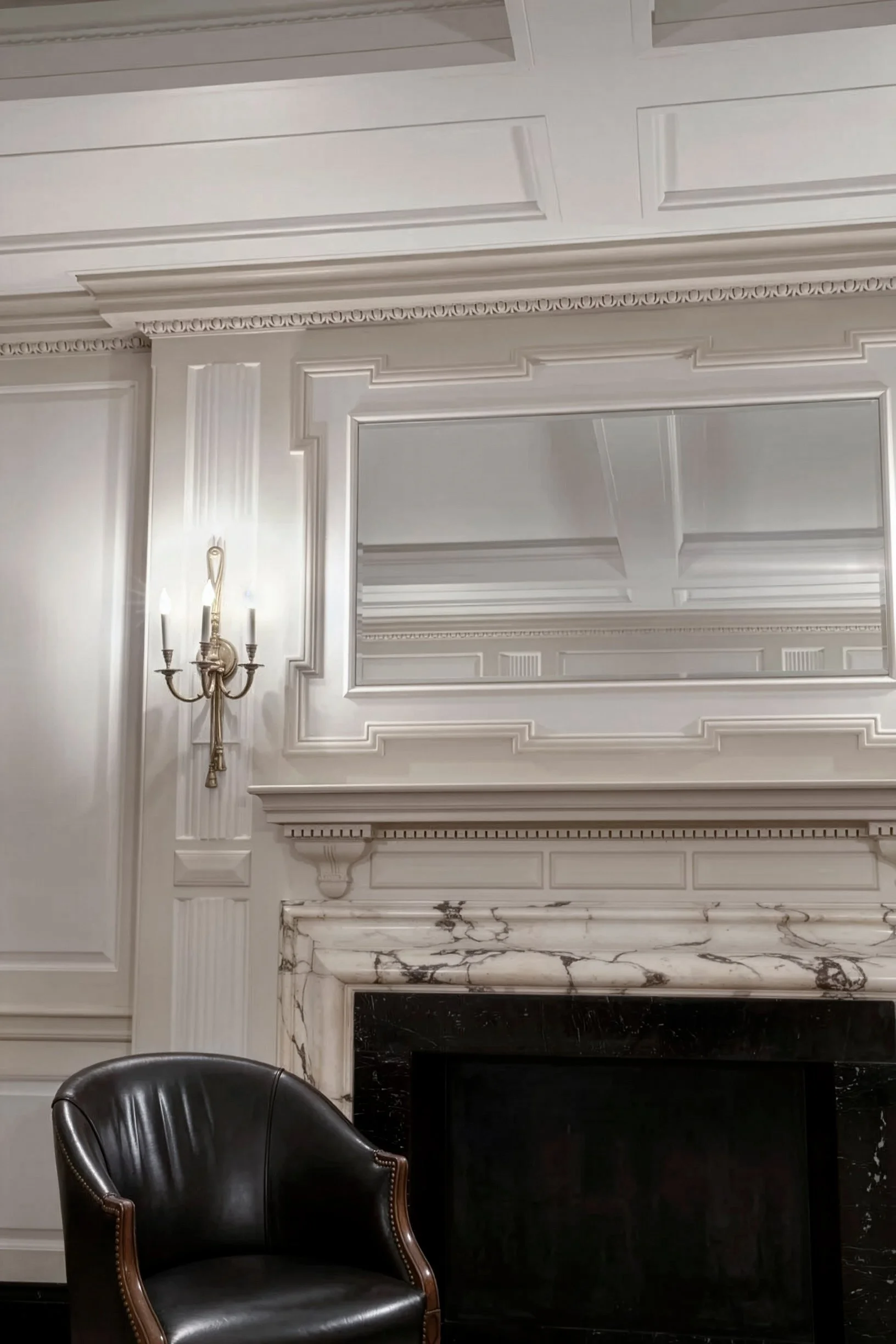 Fireplace with chair in front and mirror overhead