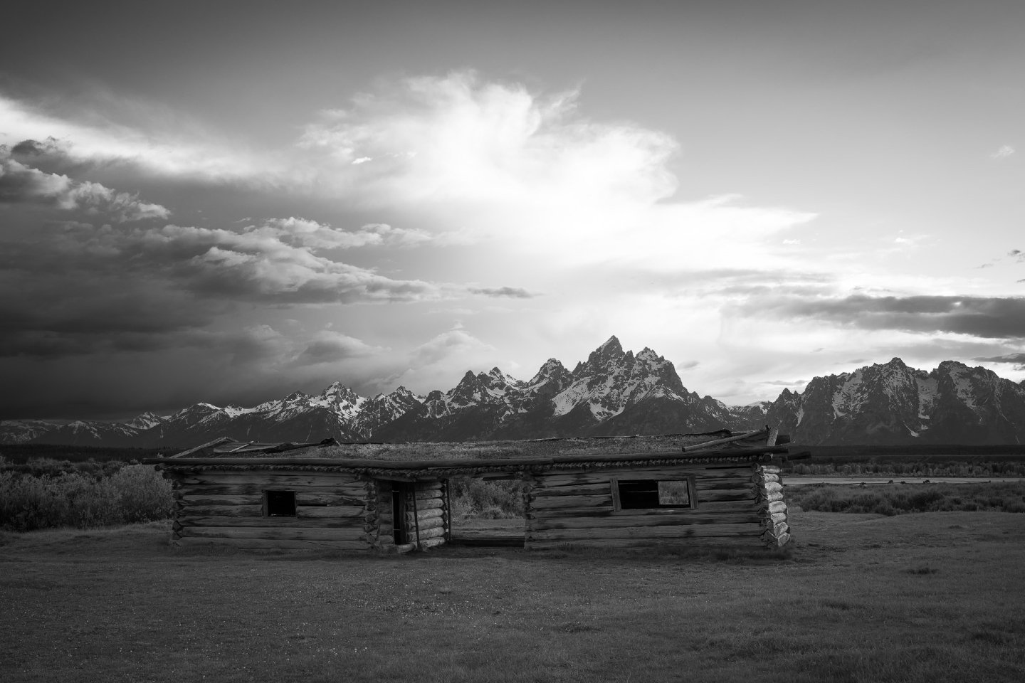 This is the historic Cunningham Cabin. 

Watching those dramatic clouds roll heavily over the jagged peaks of the Teton Range at sunset, you can almost feel the old American West.  Built back in 1888, this unique "dog-trot" cabin has weathe